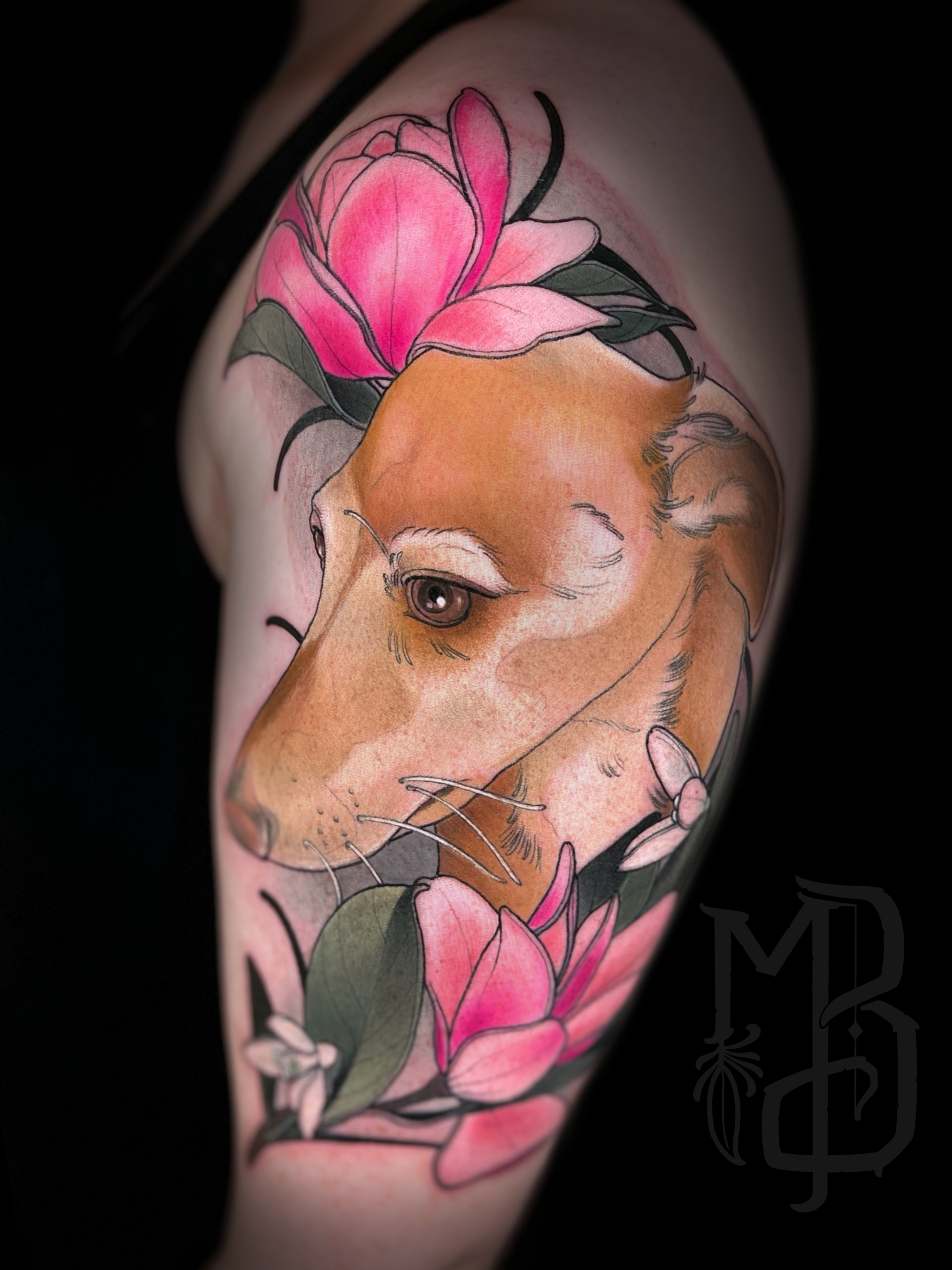 Tattoo of a dog's head portrait surrounded by pink Magnolia flowers on a person's arm.
