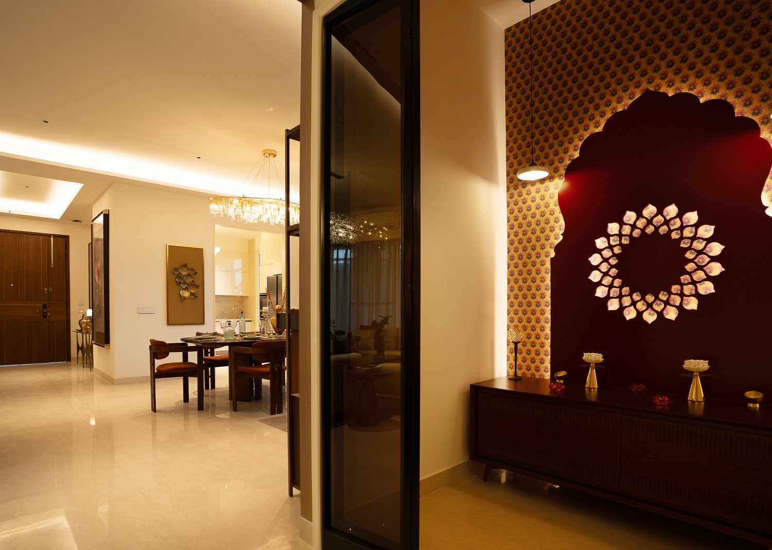 Interior view of a modern living space with a dining area, chandelier, artwork, and decorative wall with illuminated patterns.