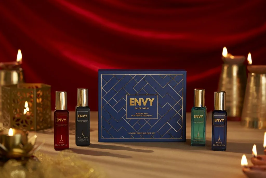 A luxury perfume gift set featuring four bottles of ENY Eau de Parfum in front of red velvet curtains and gold candles, with two decorative gold lanterns on each side.