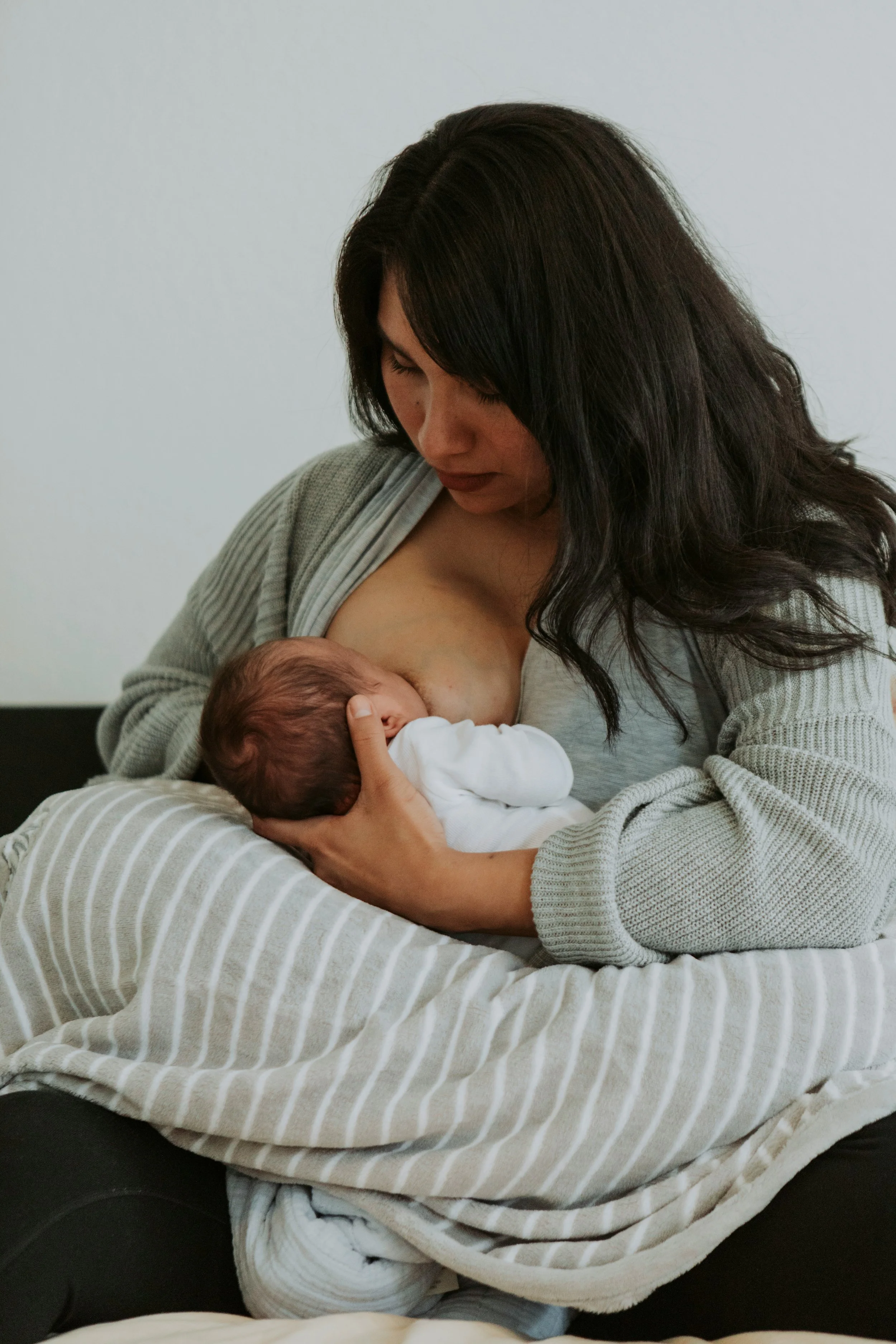 Woman breastfeeding her baby in a cozy setting.