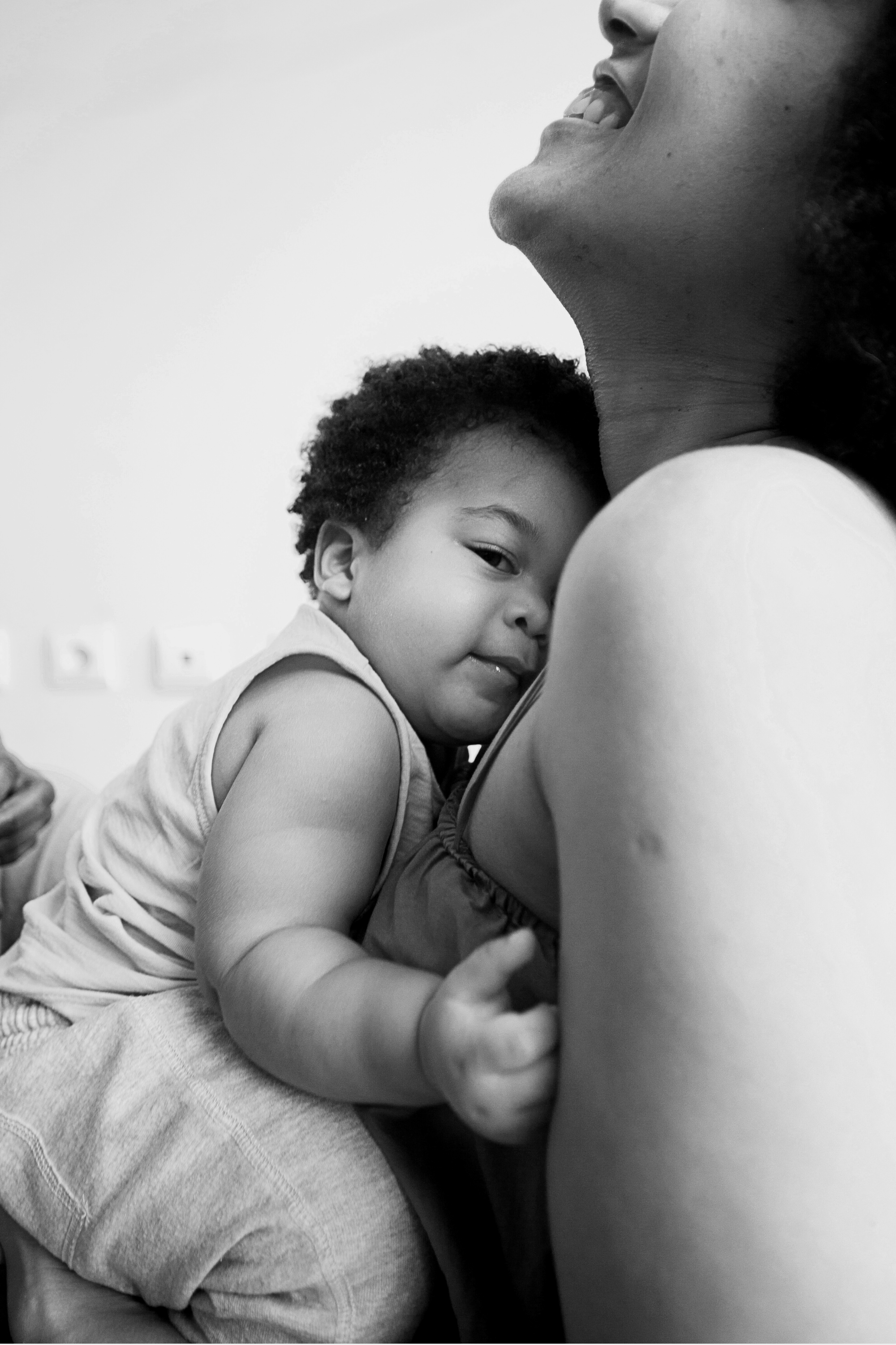 A young child hugging a woman from the front, with their face resting on her chest, both smiling. The image is in black and white.