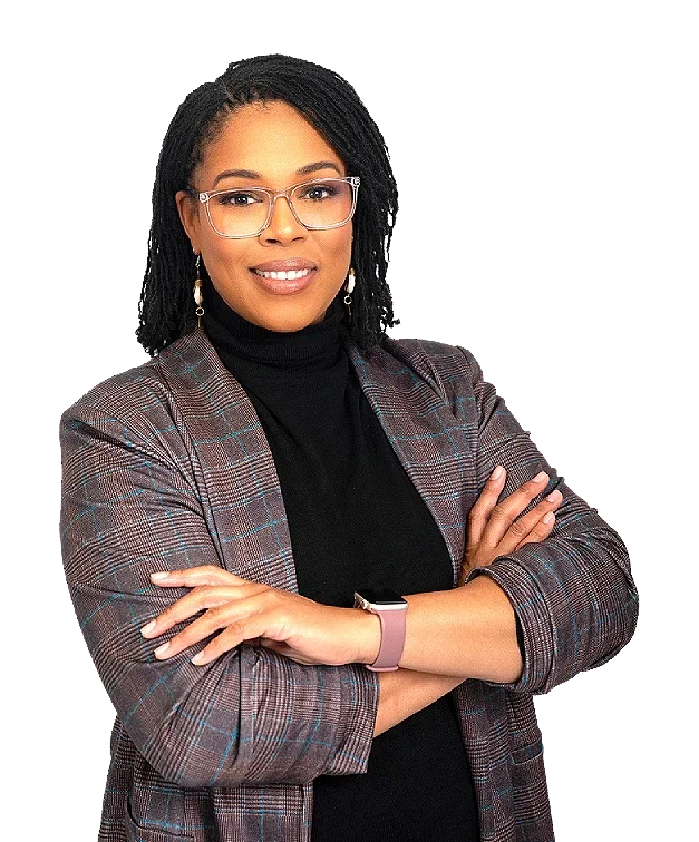 A confident woman with braided hair, glasses, and earrings, wearing a plaid blazer and black turtleneck, crossing her arms.