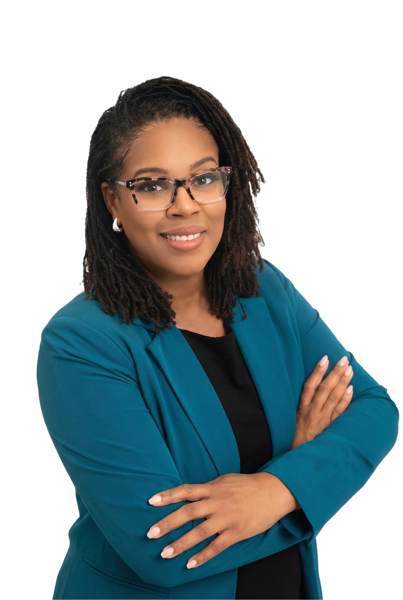 A woman with shoulder-length dreadlocks, wearing glasses, a teal blazer, and a black shirt, standing with arms crossed and smiling.