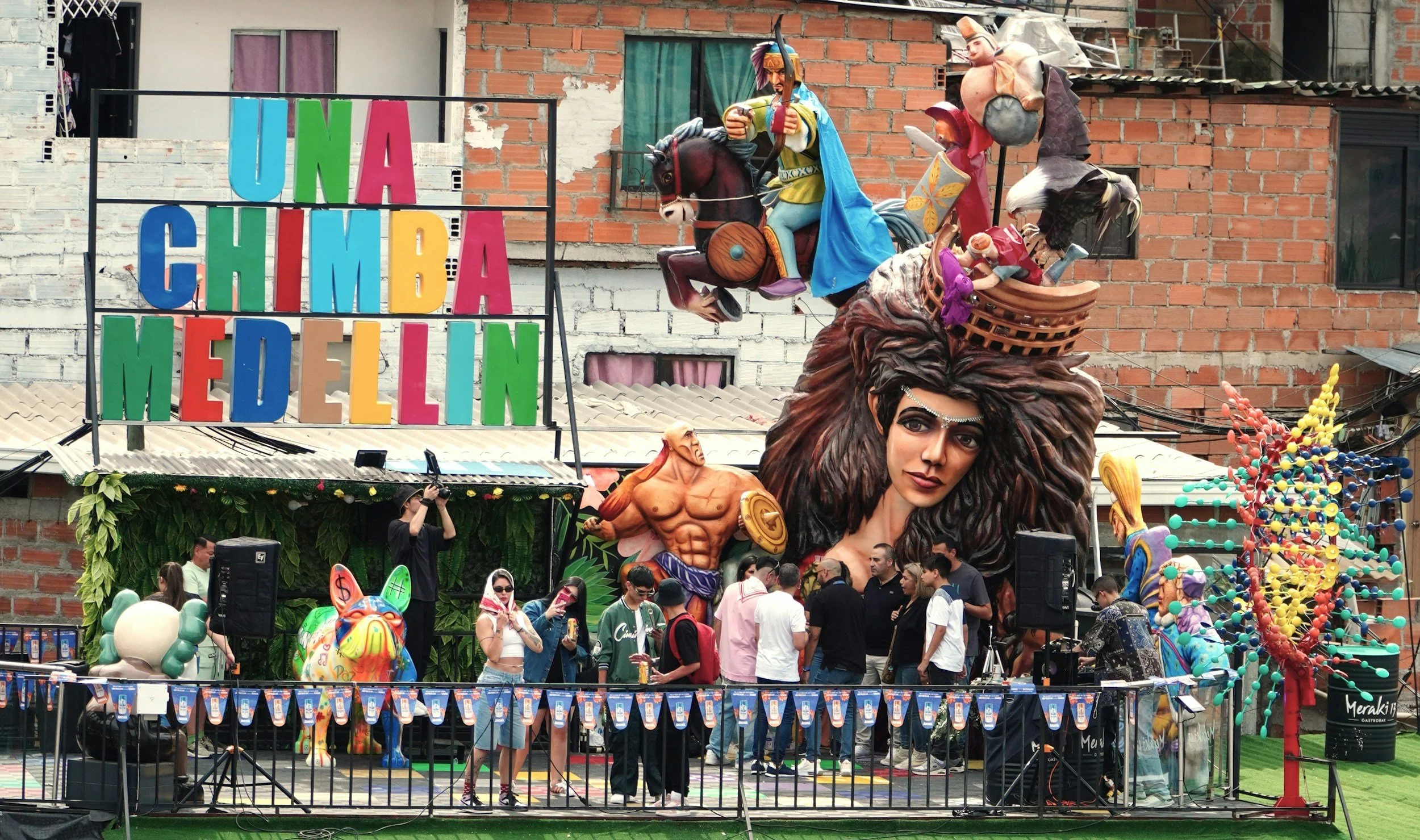 Colorful float with large sculptures, including a woman with flowing hair, a man on a horse, and various characters, with a sign reading 