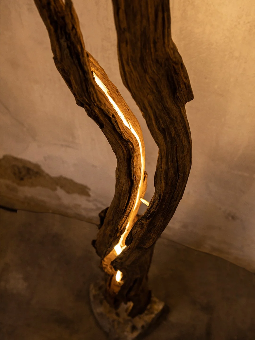 Kunstvolle Lampe aus gebogenem Holz mit einer integrierten Lichtquelle, die warmes Licht abstrahlt.