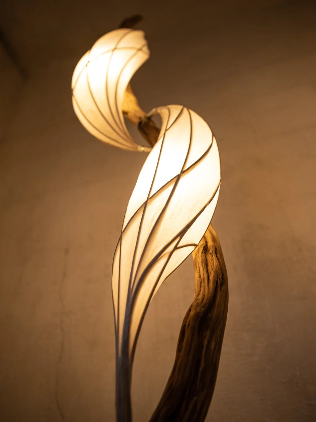 Elegante Stehlampe mit geschwungenem Holzstab und spiralförmigen Lampenschirmen aus Papier, die warmes Licht abgeben.