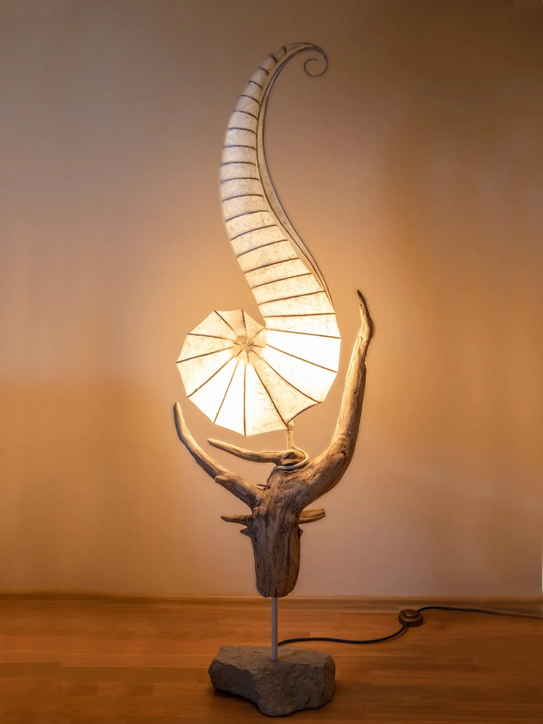 Lampenleuchte mit einem Holzstück, einem Lampenschirm und einem Lampenflügel.