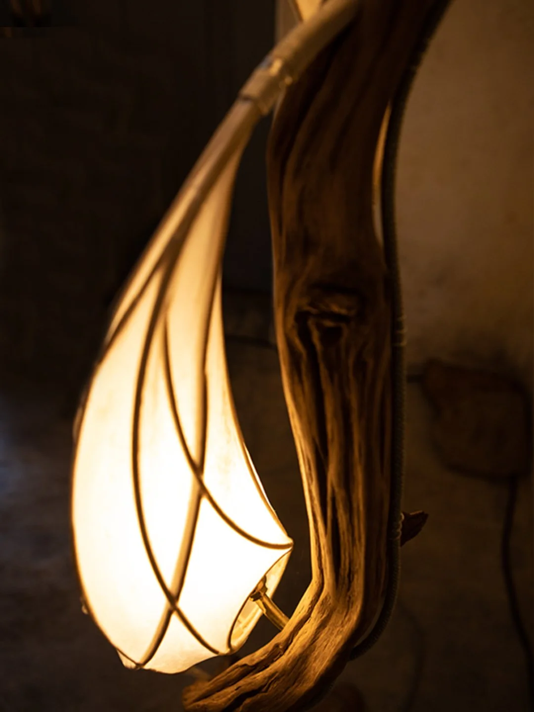 Eine elegante Wandleuchte aus Holz mit einem Leuchtenschirm aus weißem Stoff, der in einer organischen, geschwungenen Form gestaltet ist.