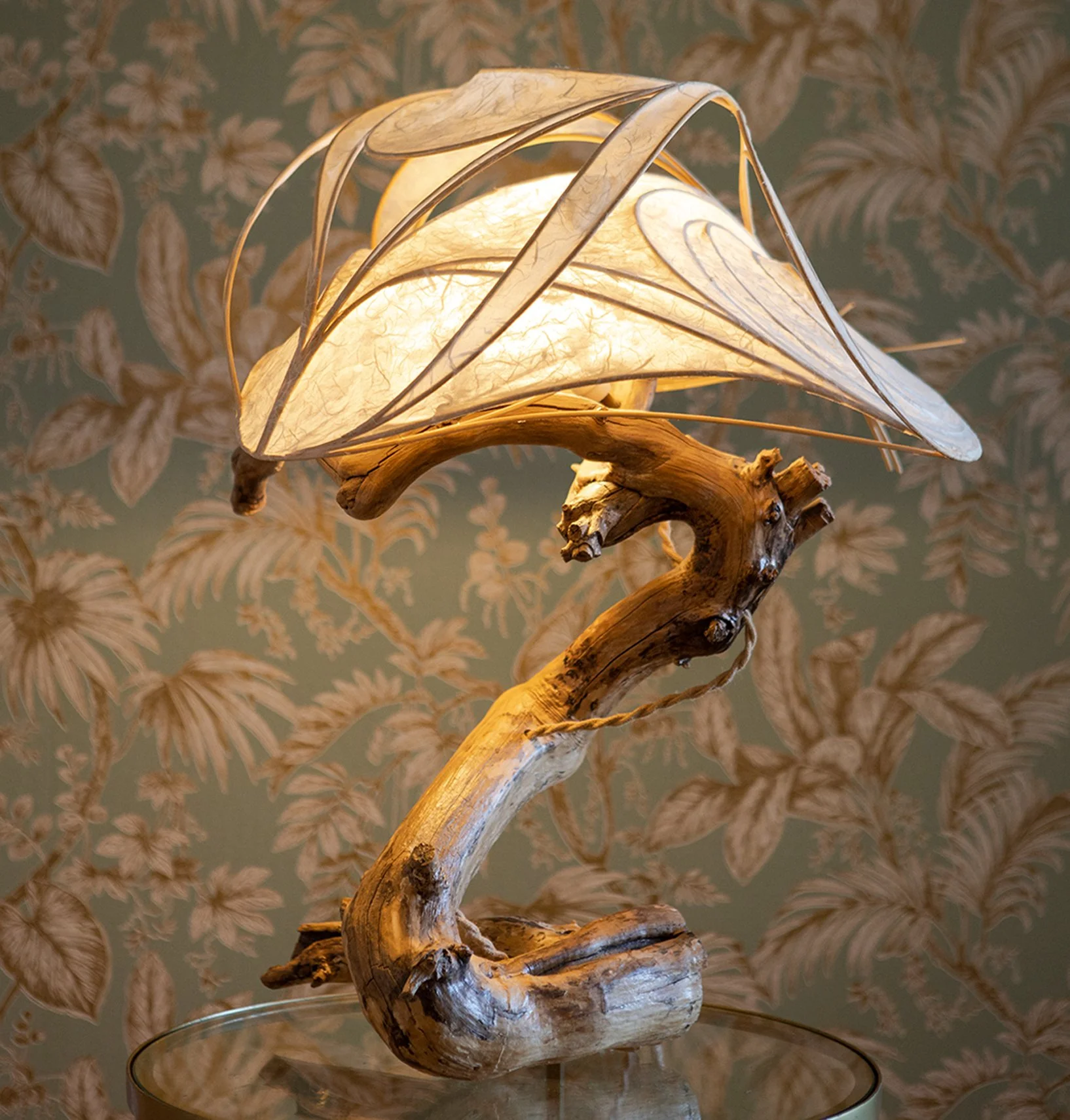 Ein Tischlampe mit einem Lampenschirm aus Papier und einem Lampenarm aus gebogenem Holz.