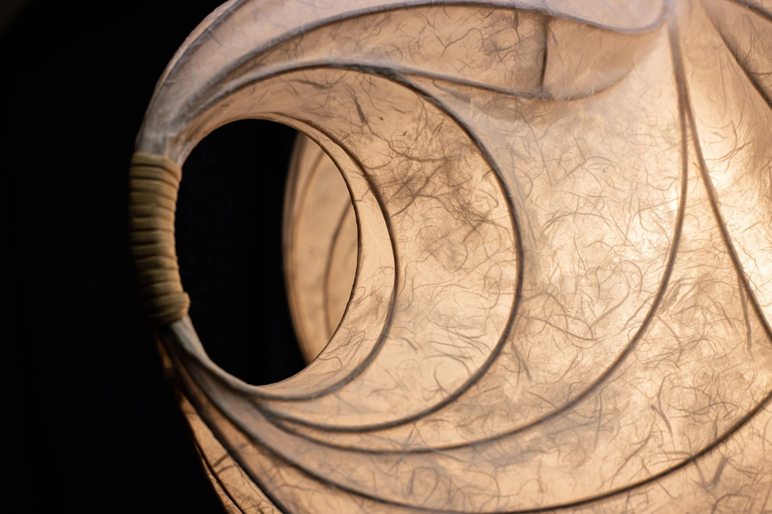 Nahaufnahme einer spiralförmigen, laminierten, transparenten Lampenschirm, der aus Papier gefertigt ist