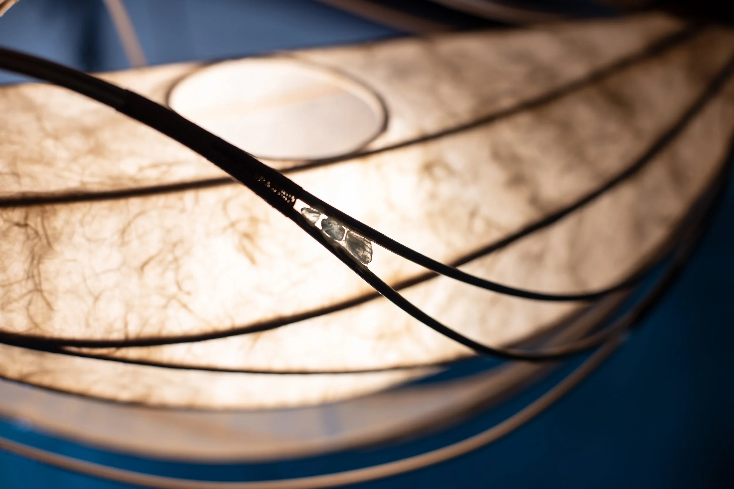 Nahaufnahme einer Lampenschirm mit mehreren Lagen aus transparentem Papier und einem schwarzen Kabel.