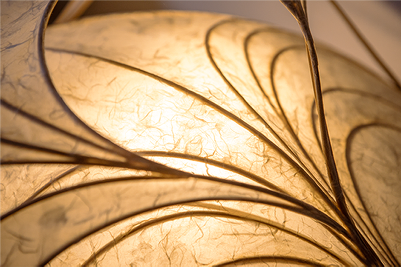 Nahaufnahme eines beleuchteten Blattdekorationsobjekts mit goldgelber, papierartiger Struktur.