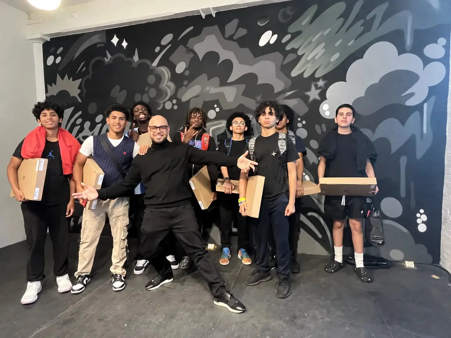 LeBron Legacy founder with young participants holding project boxes in front of a mural