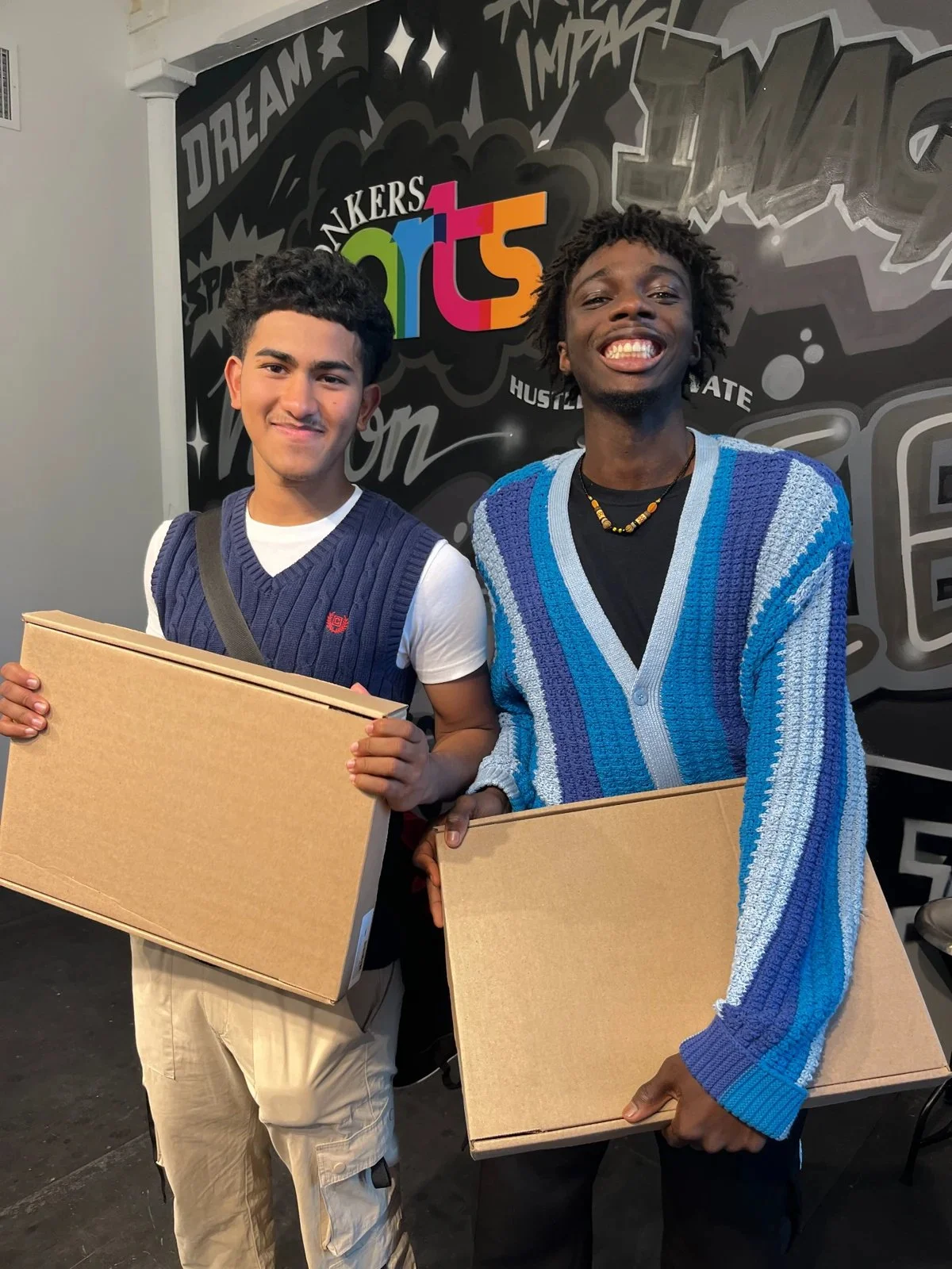 Two young program participants smiling and holding their project boxes