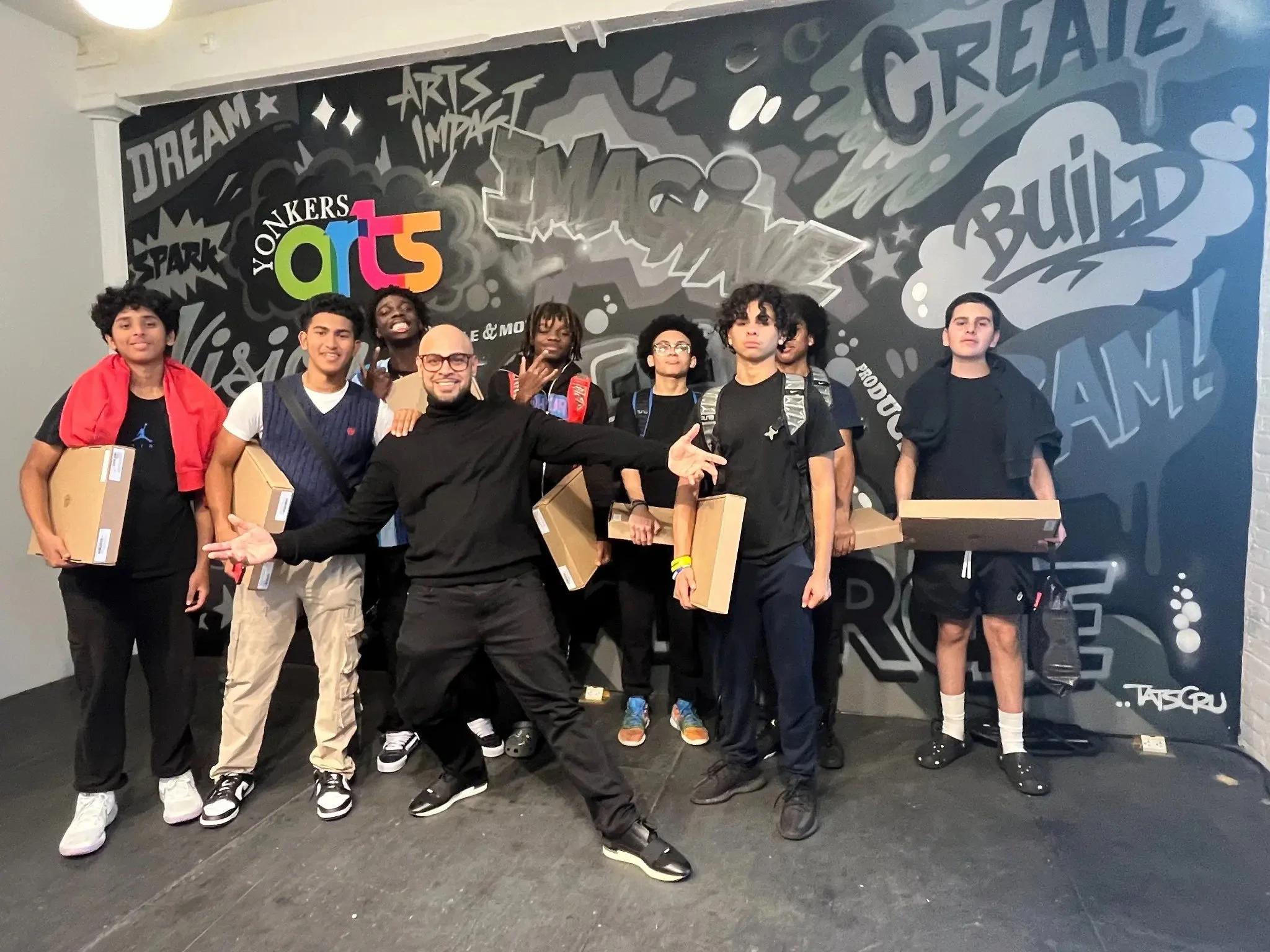 Young program participants holding their project boxes in front of a Yonkers Arts mural