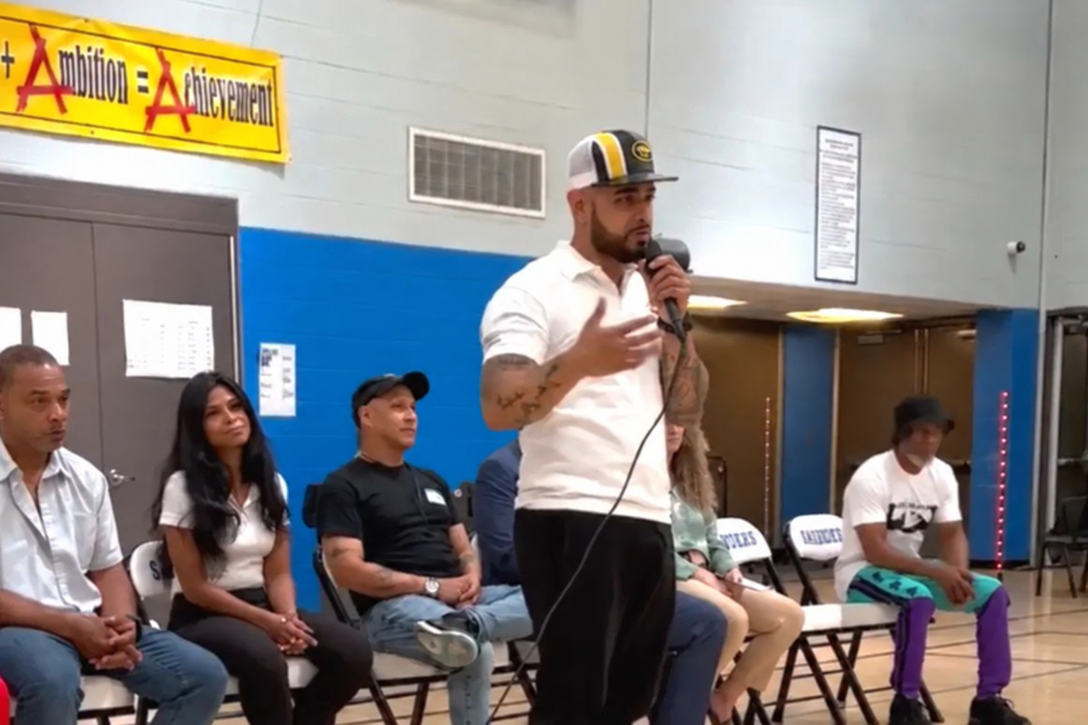 LeBron Legacy founder speaking into a microphone with a seated community panel.