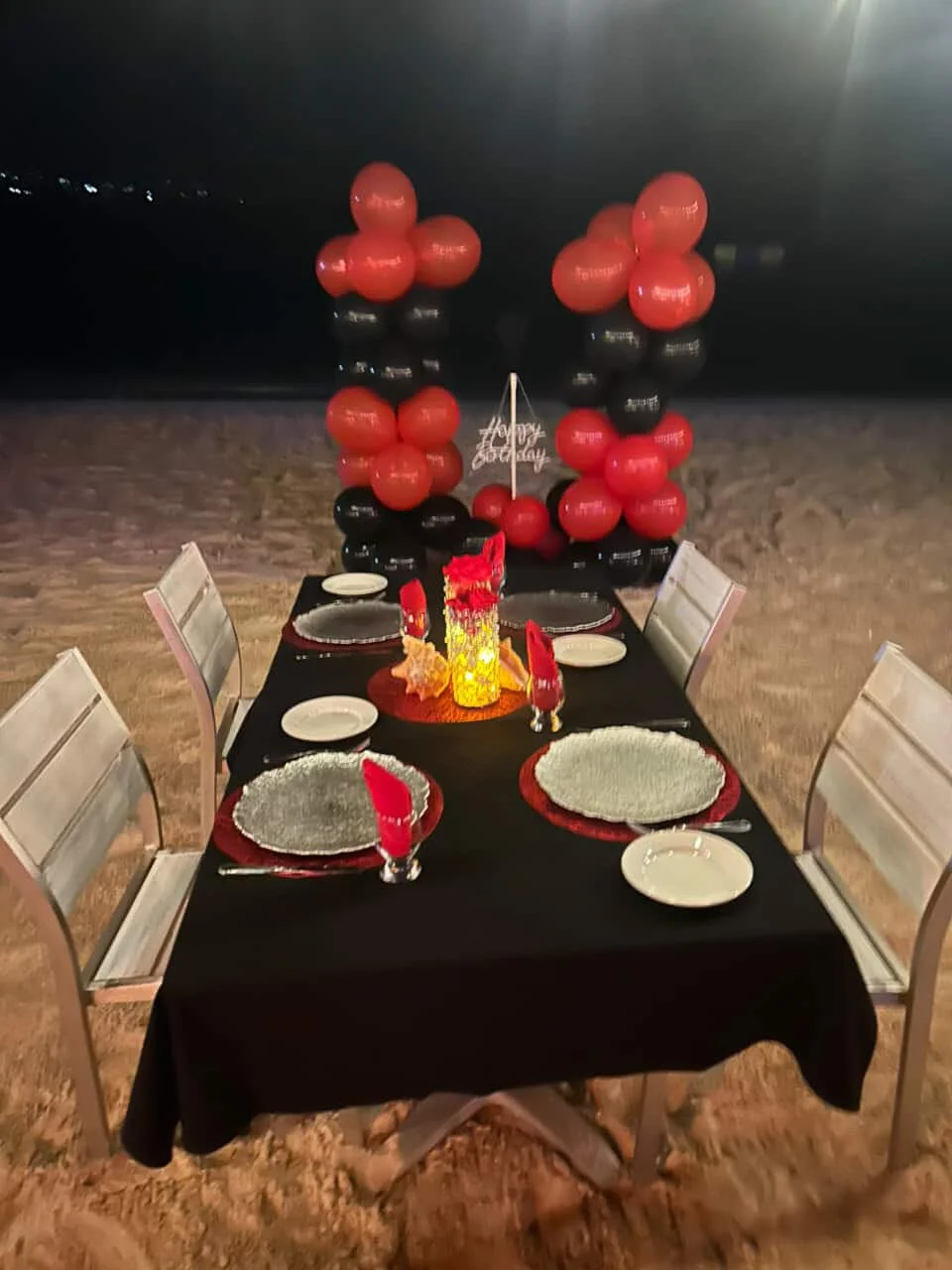 Table set for a celebration with black and red balloons in the background, a 