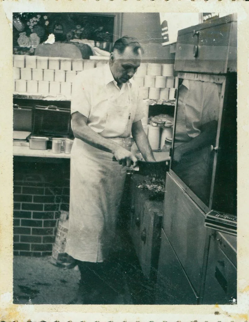 A historic photo of O.R. Gentry cooking food on a grill, wearing a white shirt and apron.