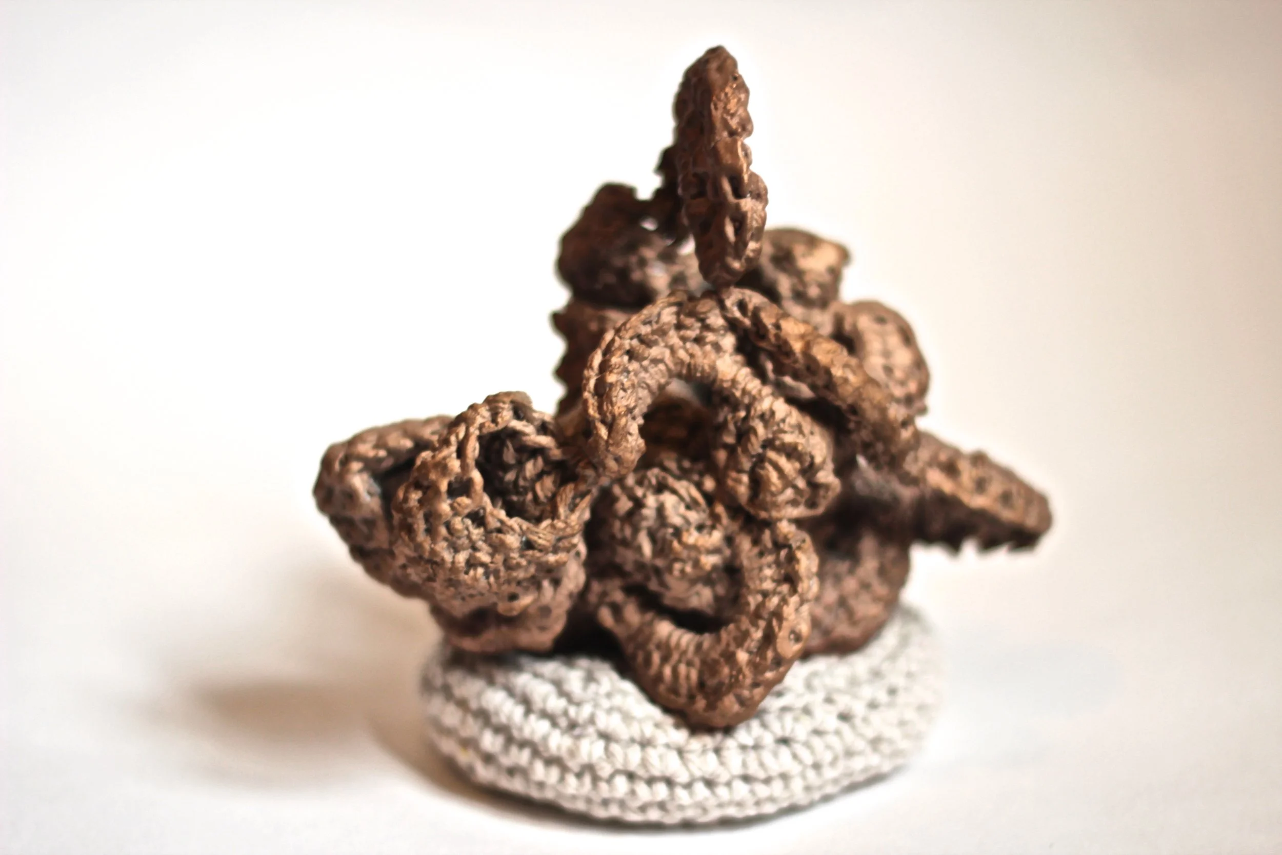 Close-up of a cluster of textured, dark brown rocks or crystals on a white surface.