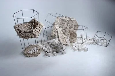 Abstract art installation with wireframe geometric shapes and irregular white and gray textured objects.