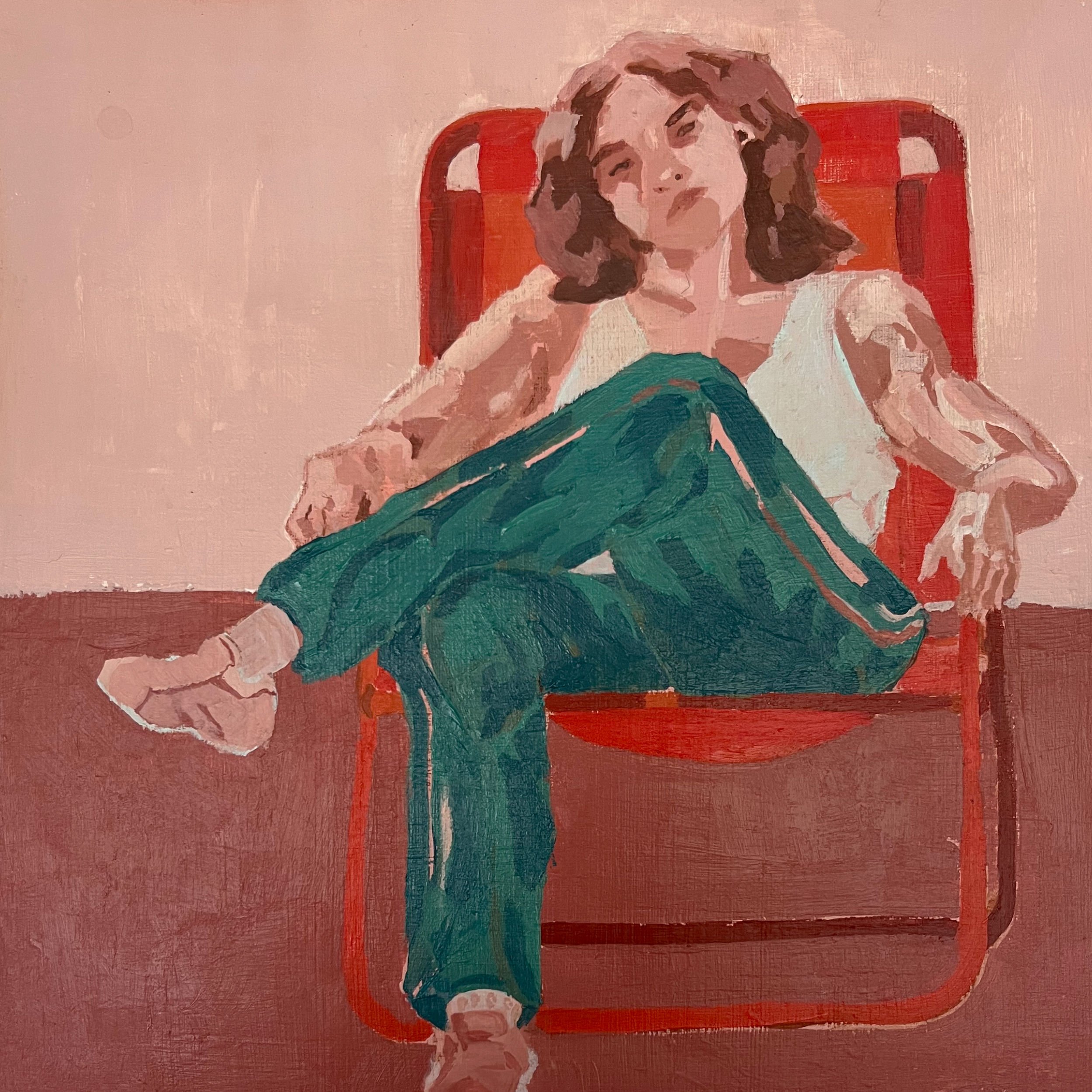 A woman with curly hair is sitting on a red chair, wearing a white top and teal pants, with her hand resting on a white surface. The background is a light pink wall.