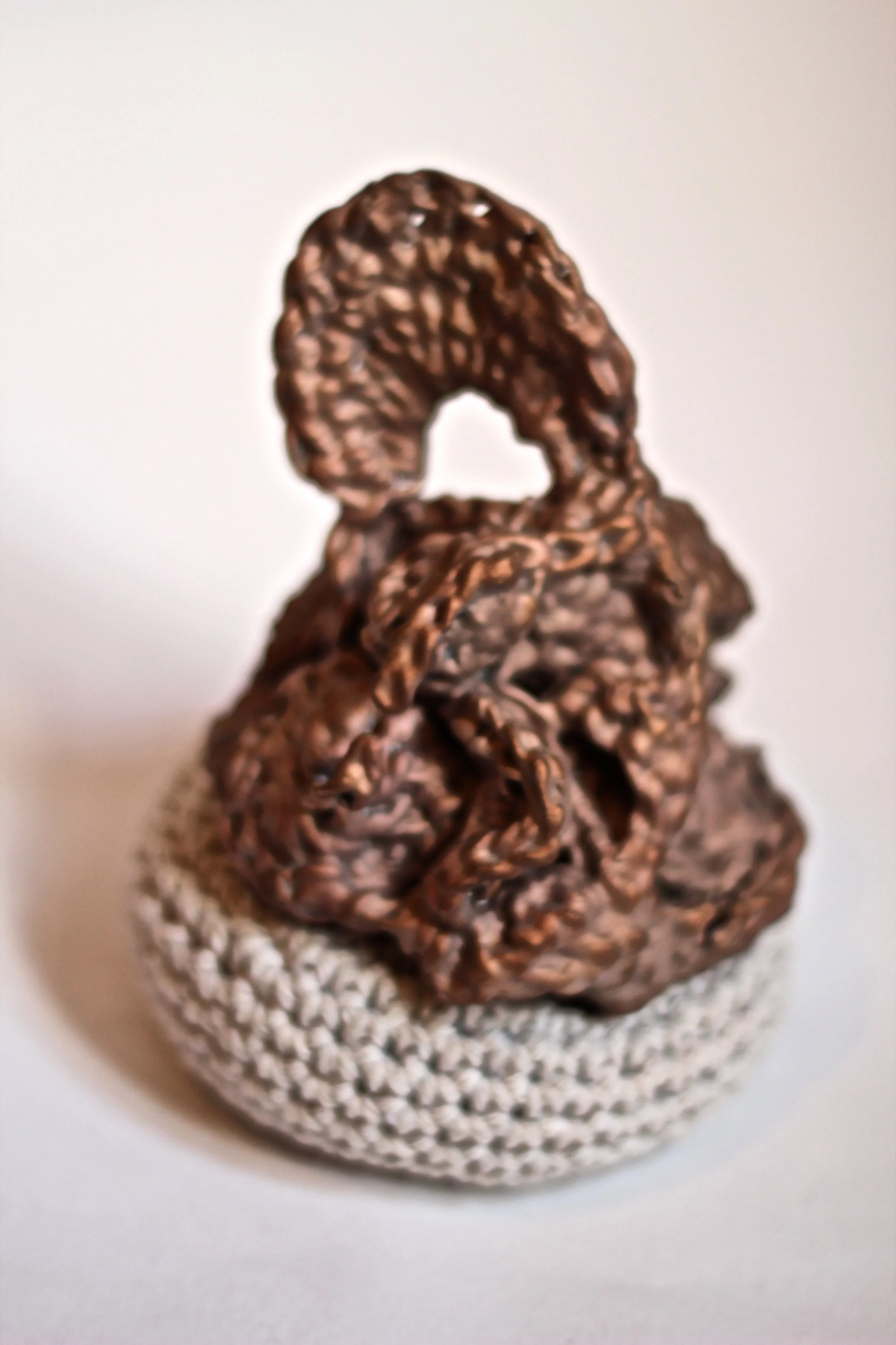 A close-up of a chocolate metallic Eiffel Tower figurine on a white textured base