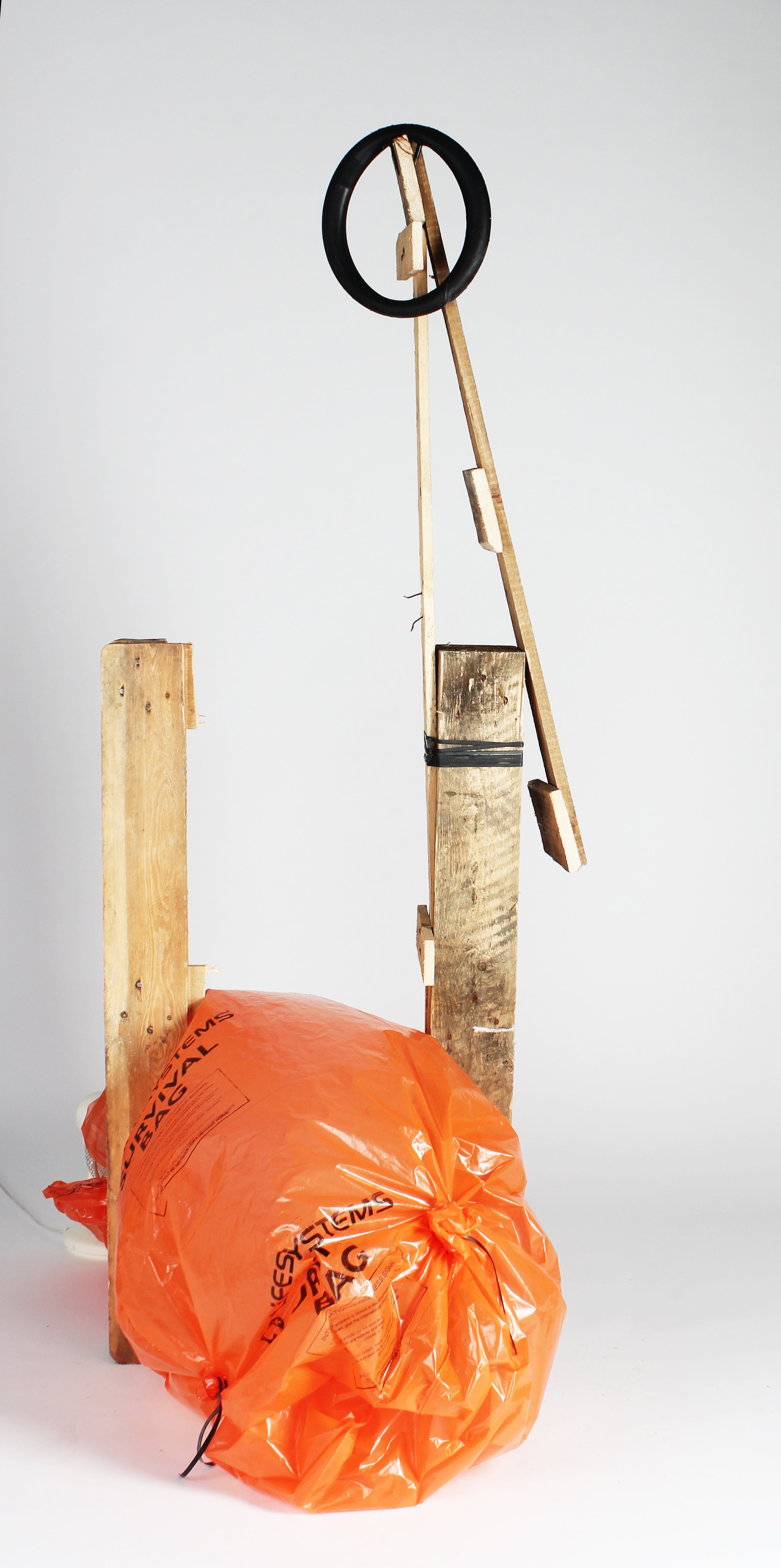 Construction site with wooden planks, a black rubber ring, and a bright orange safety bag or tarp.