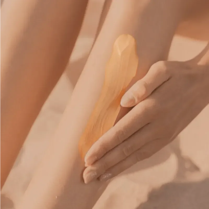 A person applying a soothing massage with a wooden tool onto someone’s leg, with the person’s hand gently pressing and the leg’s skin visible.