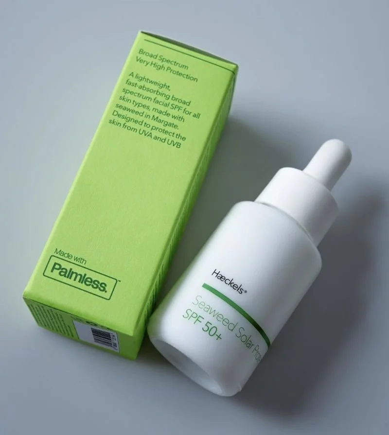 A white bottle of Helclean Seaweed Solar Protection SPF 50+ sunscreen next to a green box with product information.