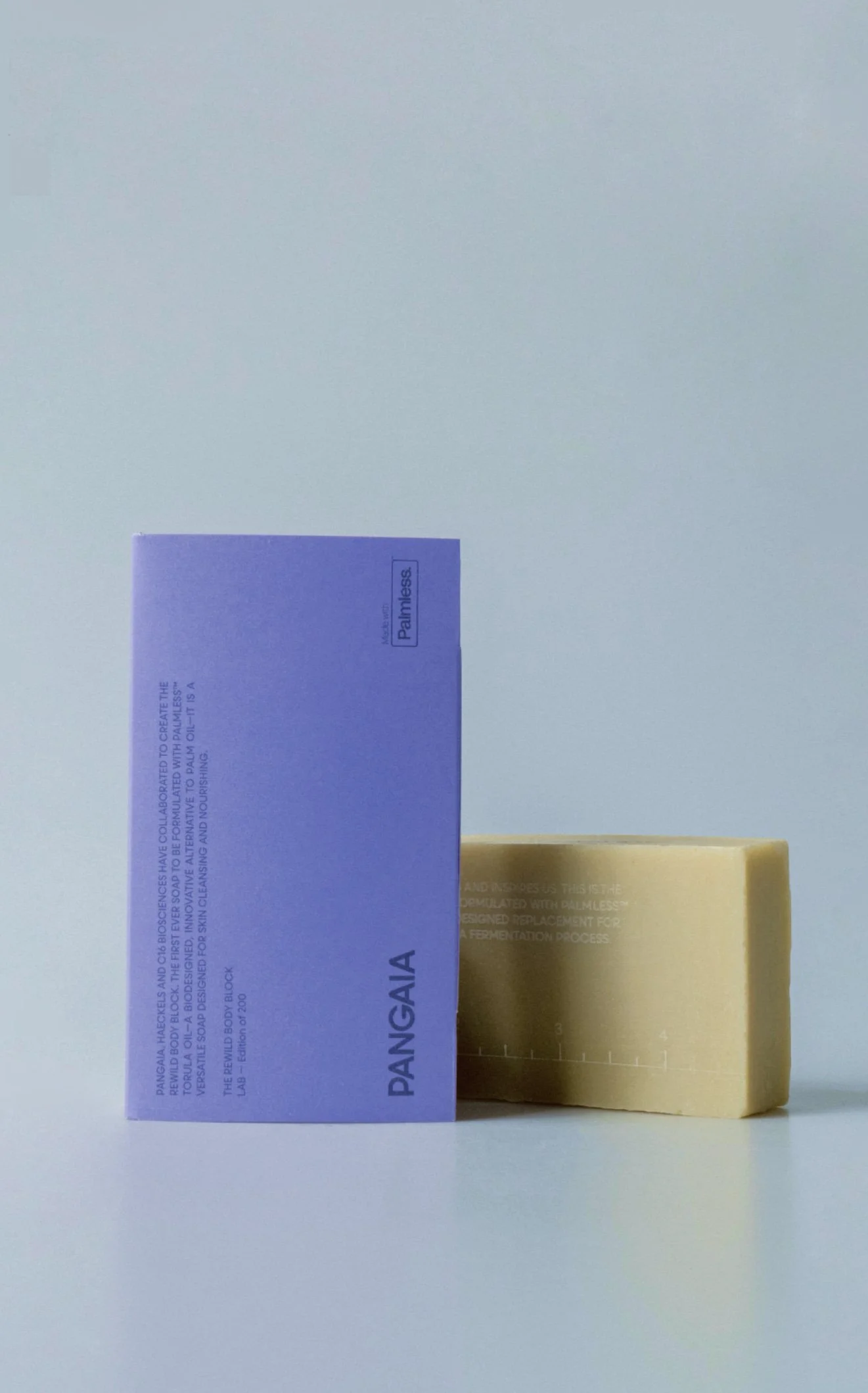 A purple box with text and a logo and a beige soap bar with measurement markings on a light surface.