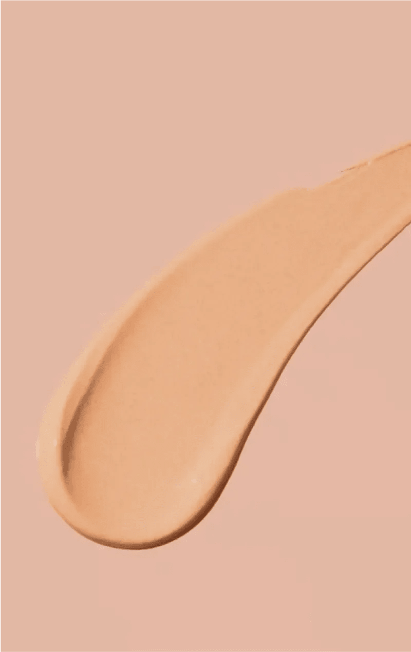 A streak of beige foundation makeup on a skin-colored background.
