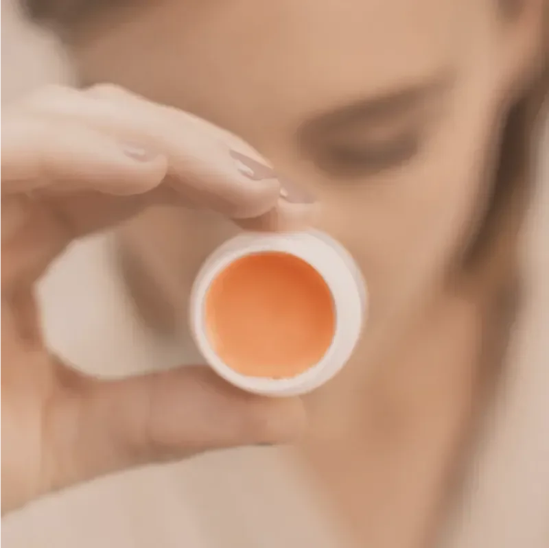 Person holding orange pill bottle close to mouth, about to take medication.