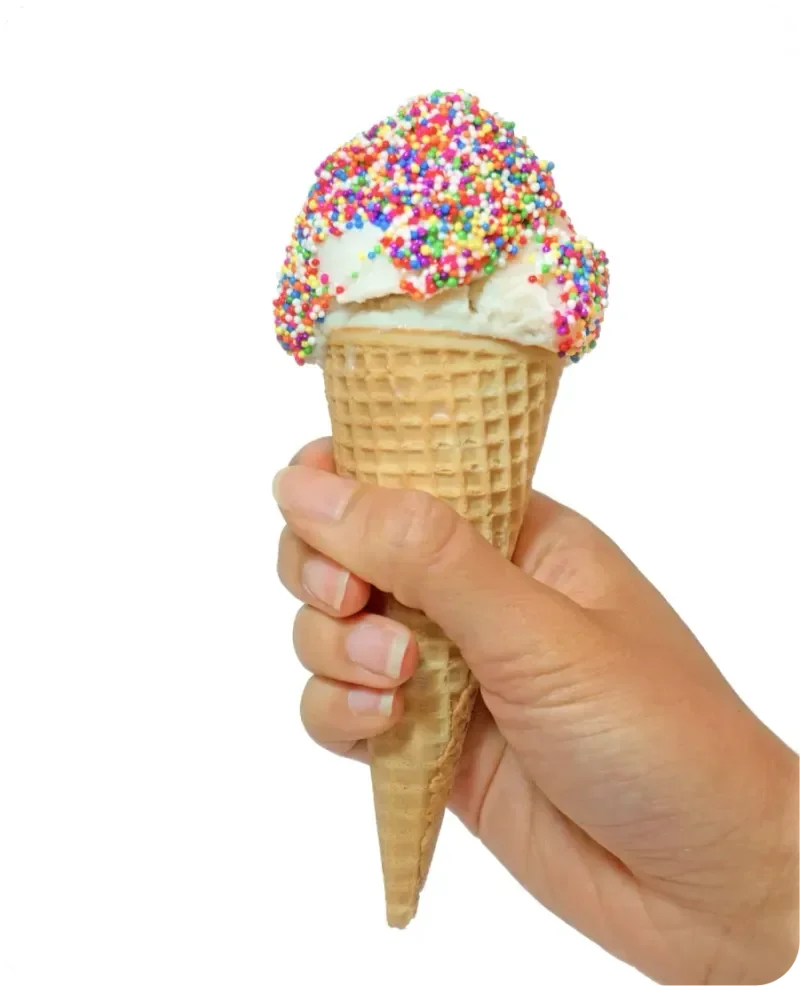 Hand holding a vanilla ice cream cone topped with colorful sprinkles against a white background.