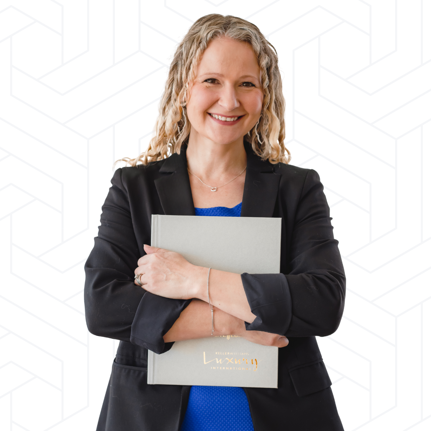 A smiling woman with curly blonde hair, wearing a black blazer and blue top, holding a gray folder with gold lettering, standing against a white background with light hexagon pattern.