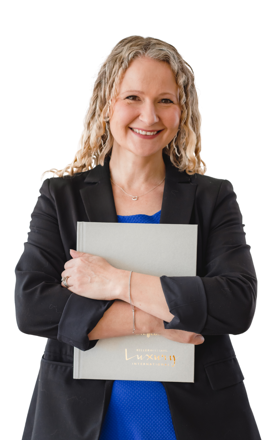 A smiling woman with curly blonde hair wearing a black blazer, holding a gray folder, standing against a black background.