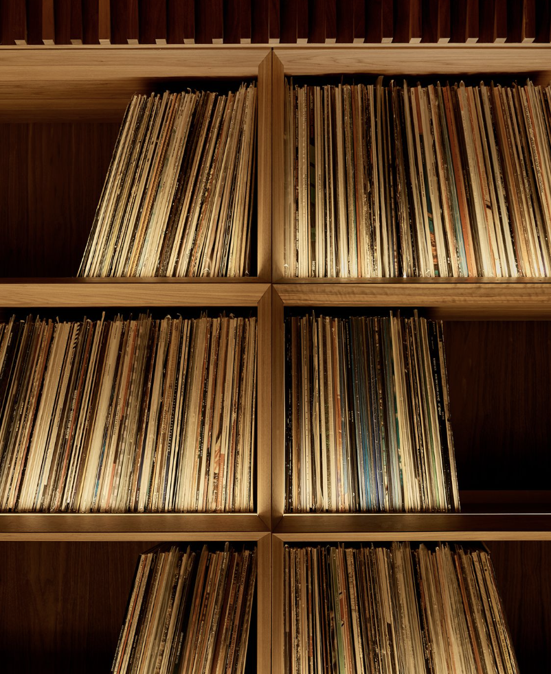 A wooden bookshelf filled with vinyl records arranged vertically.