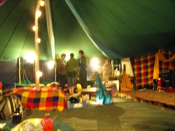 Group of people inside a decorated tent with warm lighting and colorful textiles.
