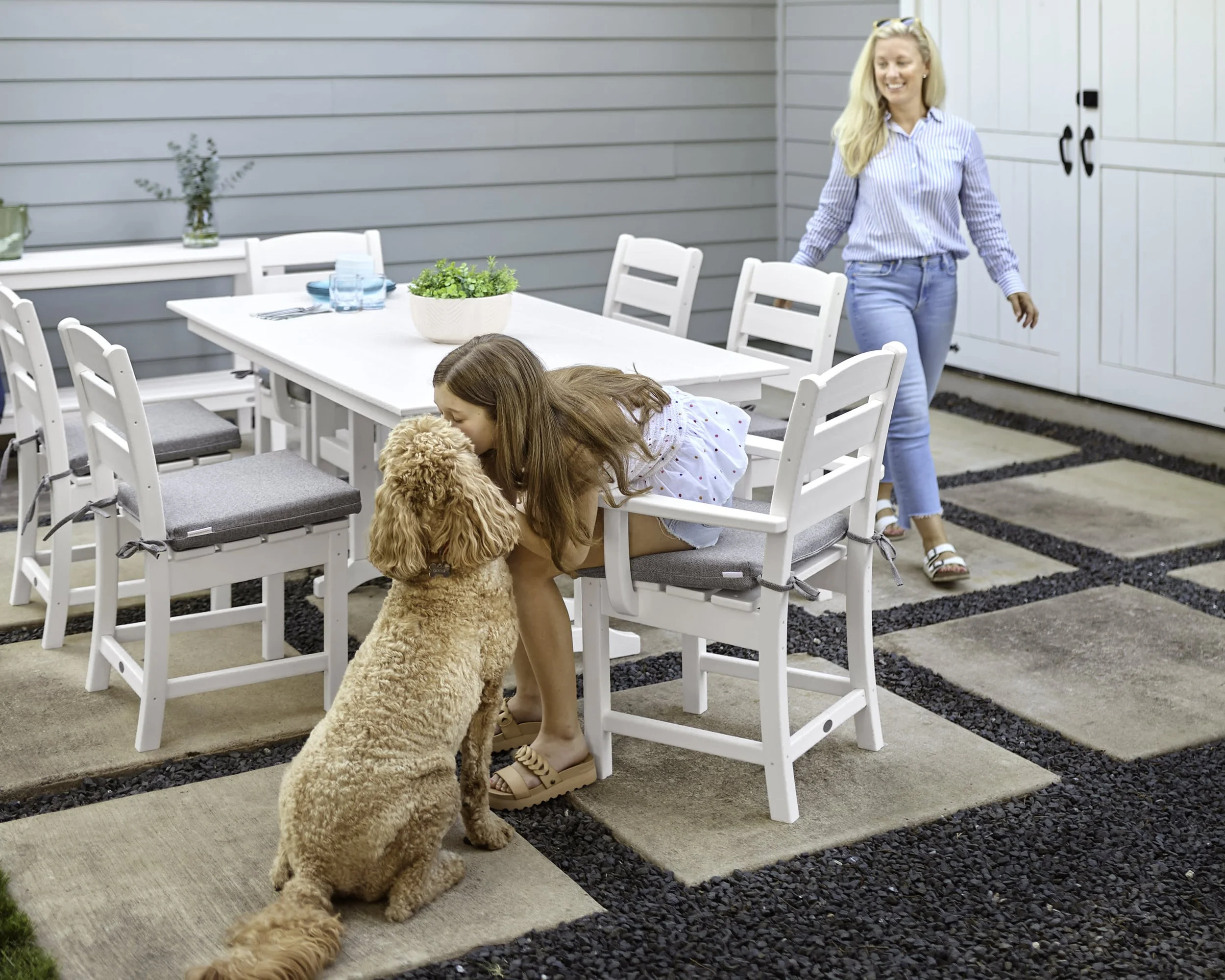 Family gathering around a white POLYWOOD outdoor dining table with matching patio chairs