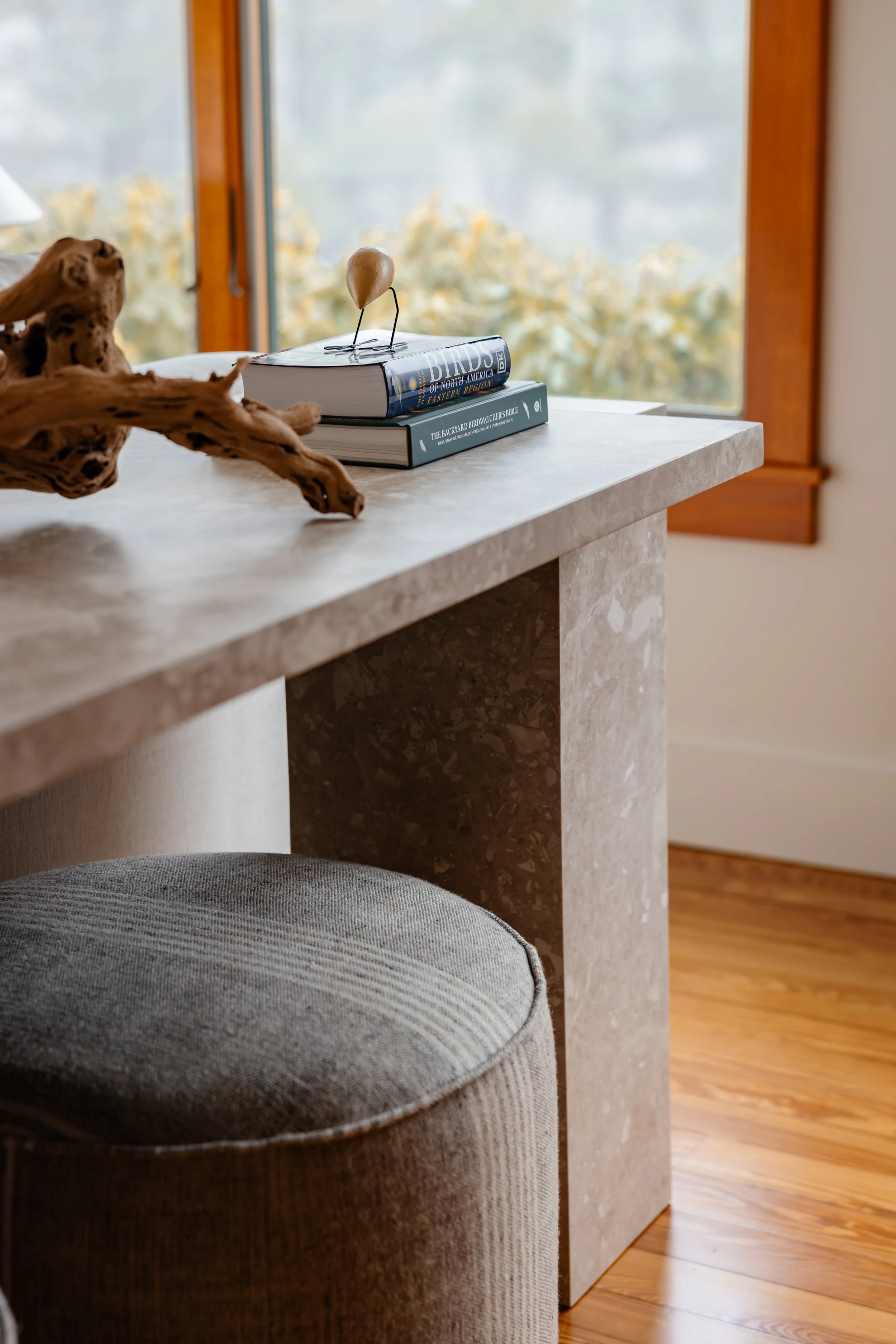 Stone console table with stacked books, wood decor, and soft natural light.