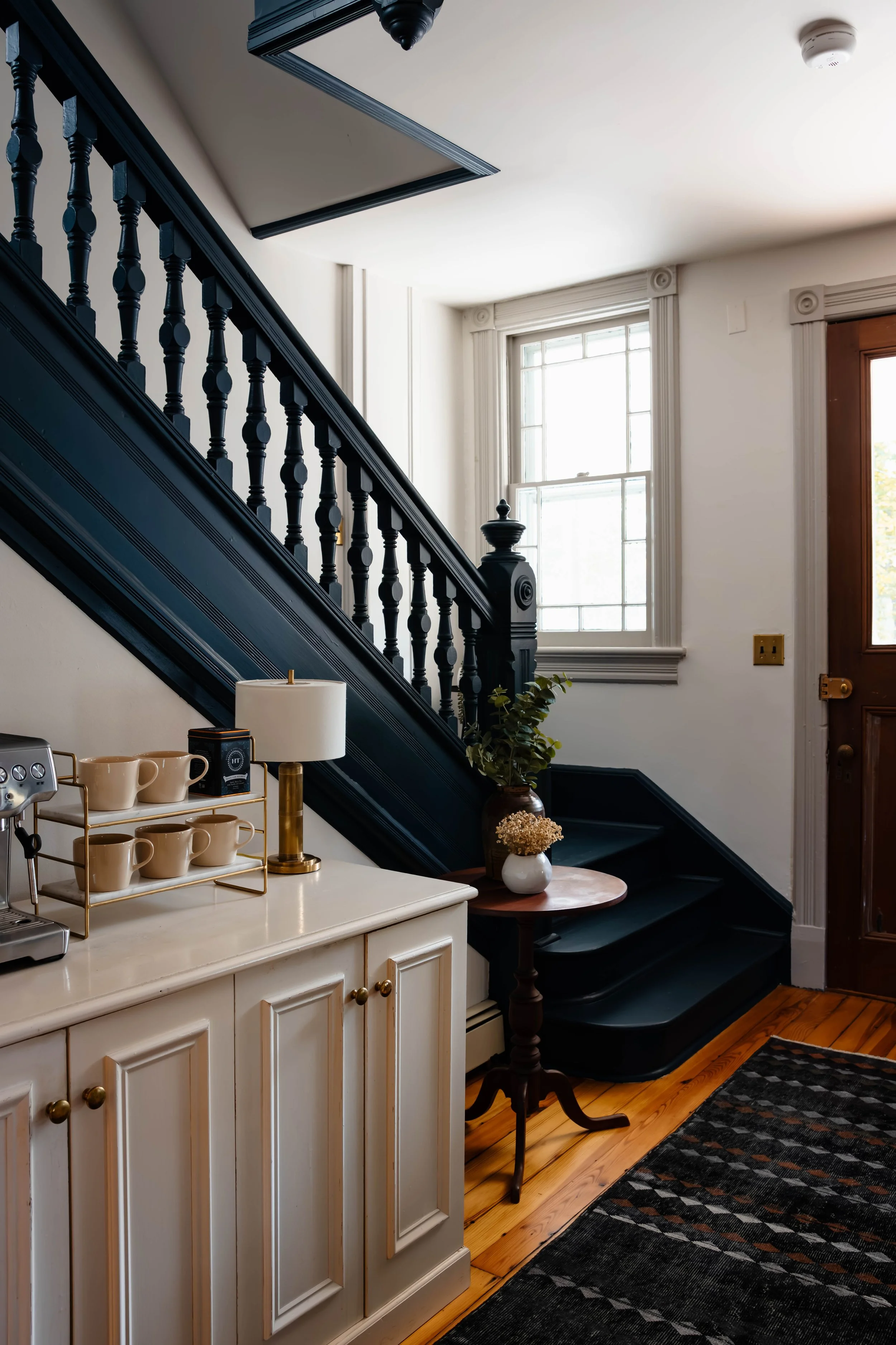 Office entry with paneled walls, painted stair railing, and styled coffee station vignette