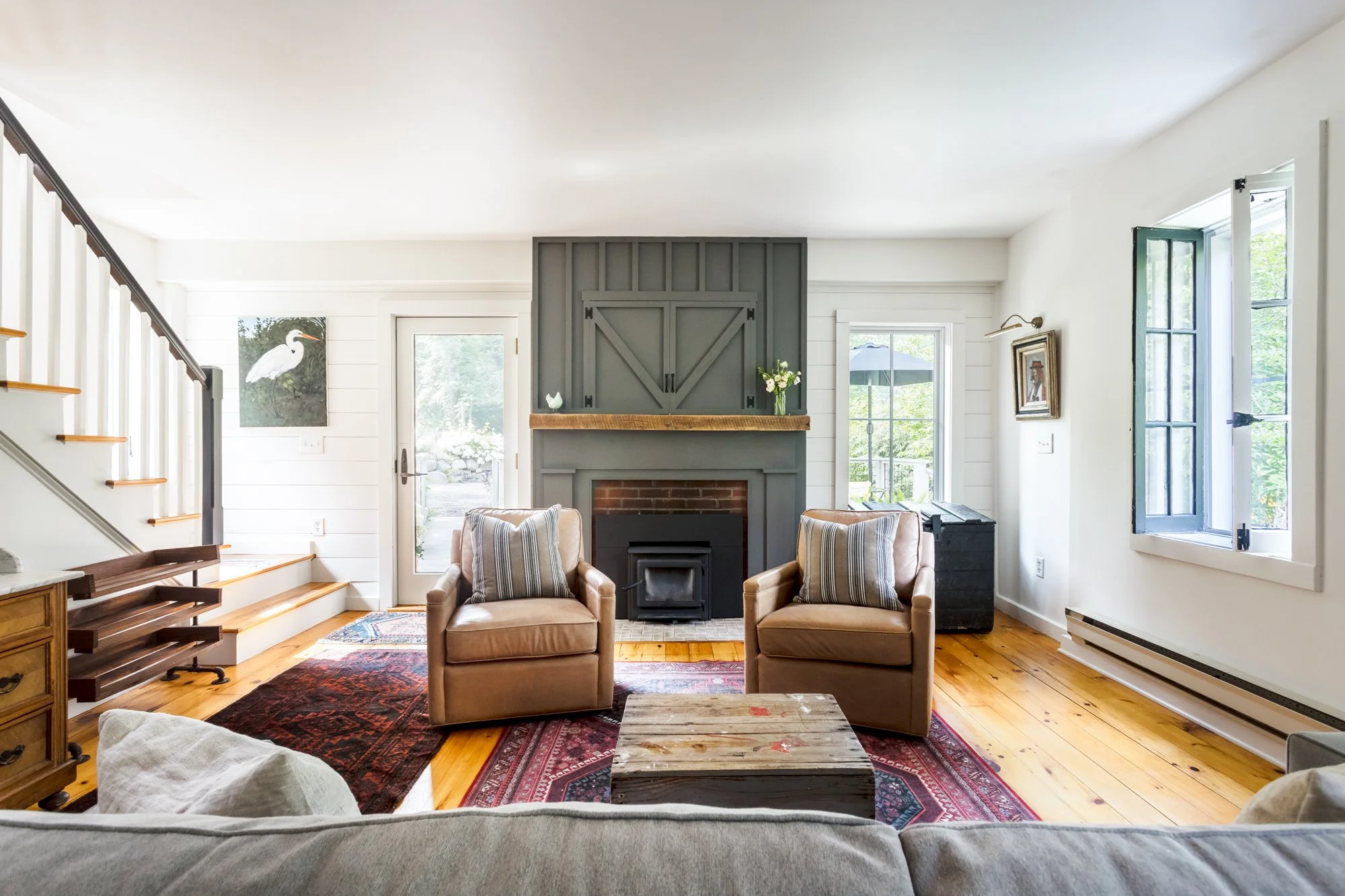 Living room with green fireplace surround, wood floors, and leather armchairs.