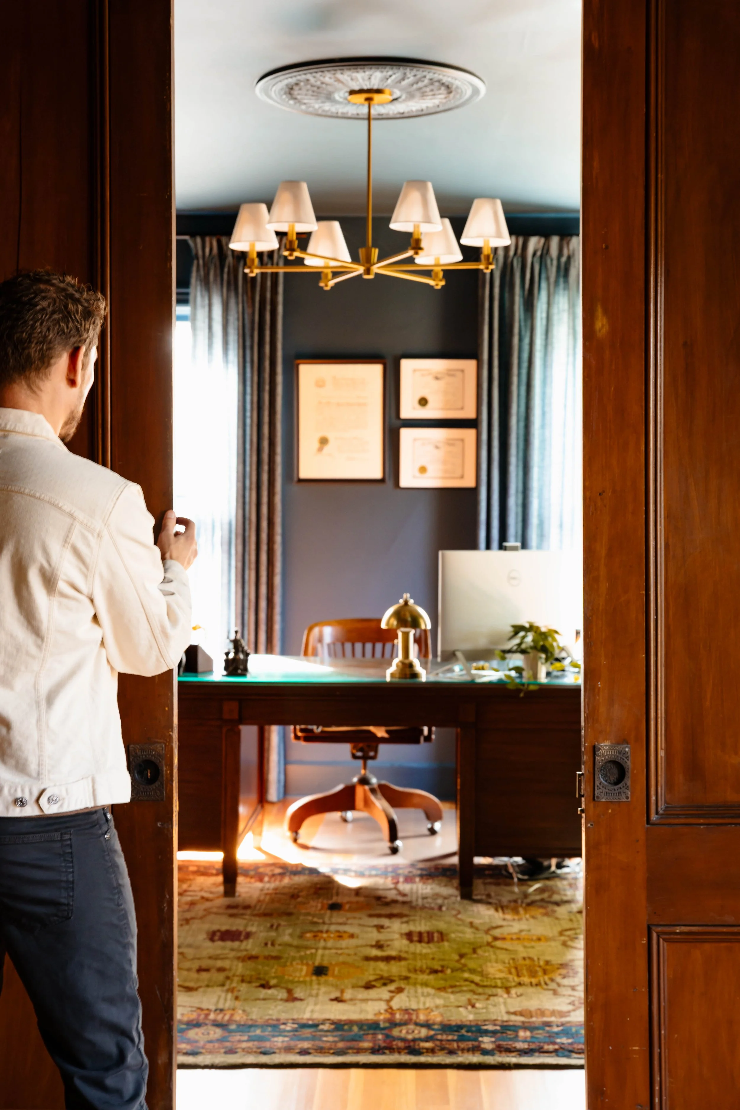 View into principal office through original wood doors with vintage desk and deep blue walls in New Paltz NY