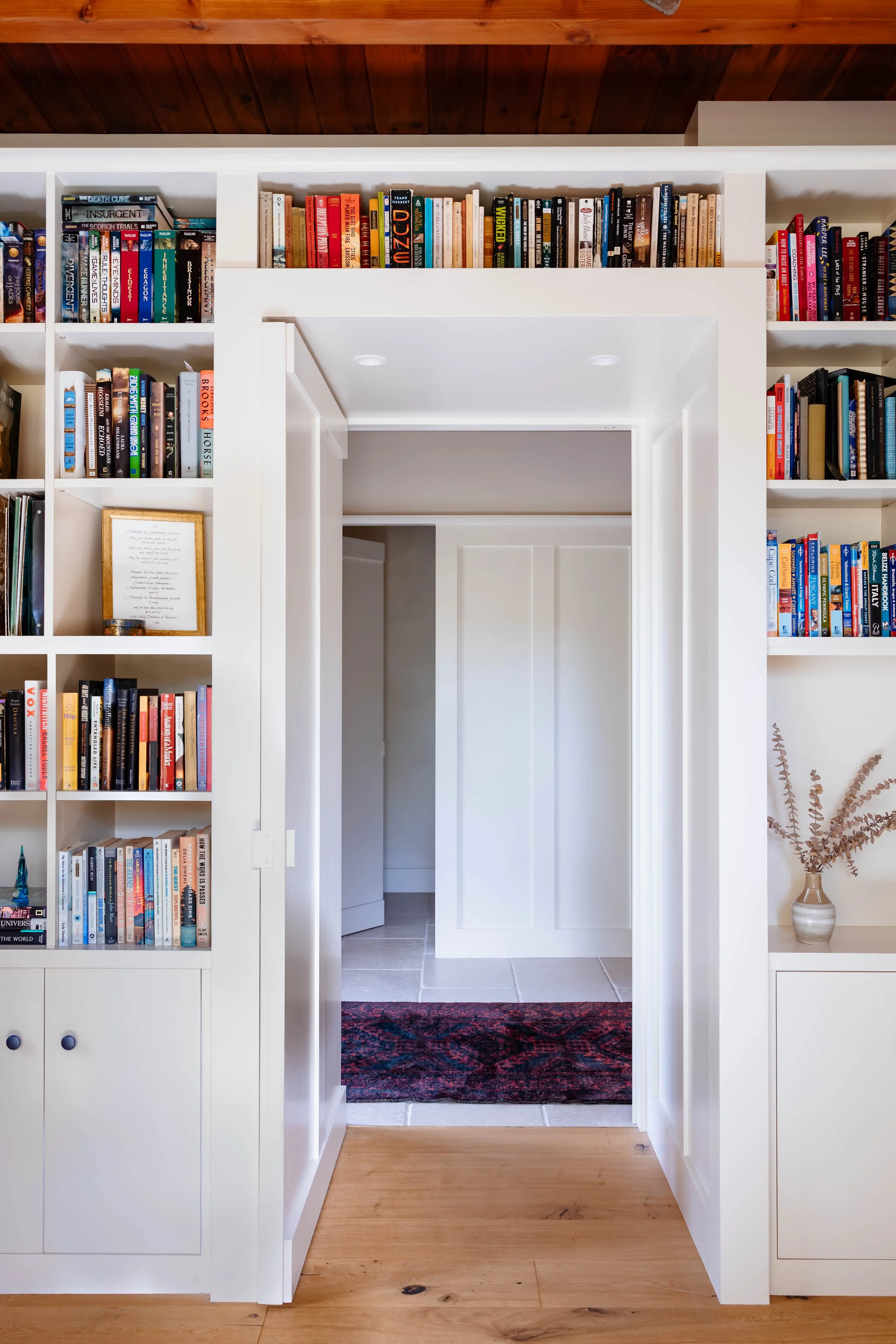 Custom built-in bookshelves framing a doorway in a thoughtfully renovated Hudson Valley straw bale home.