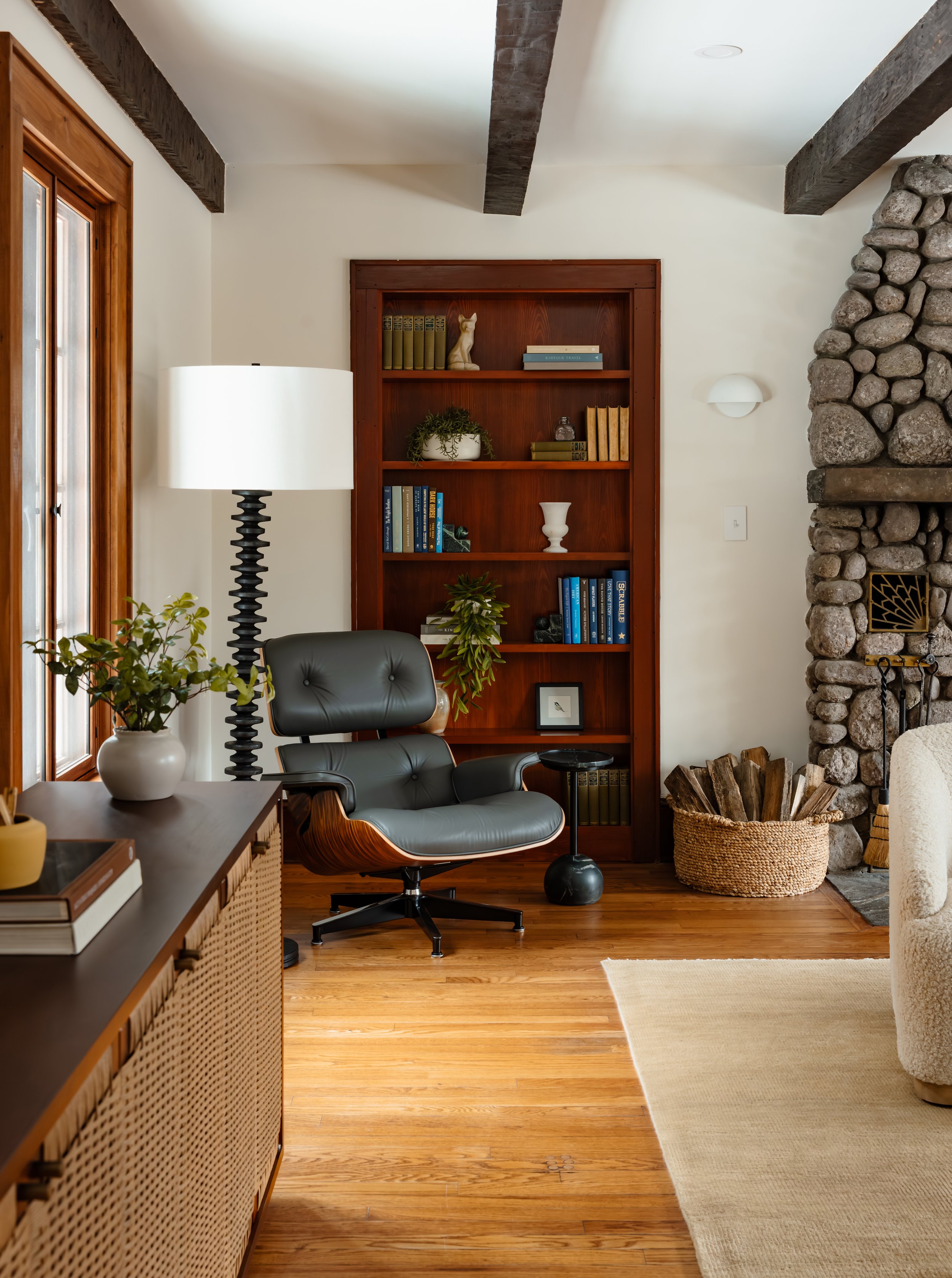 Reading nook with built-in wood bookcase, black leather lounge chair, and stone fireplace.
