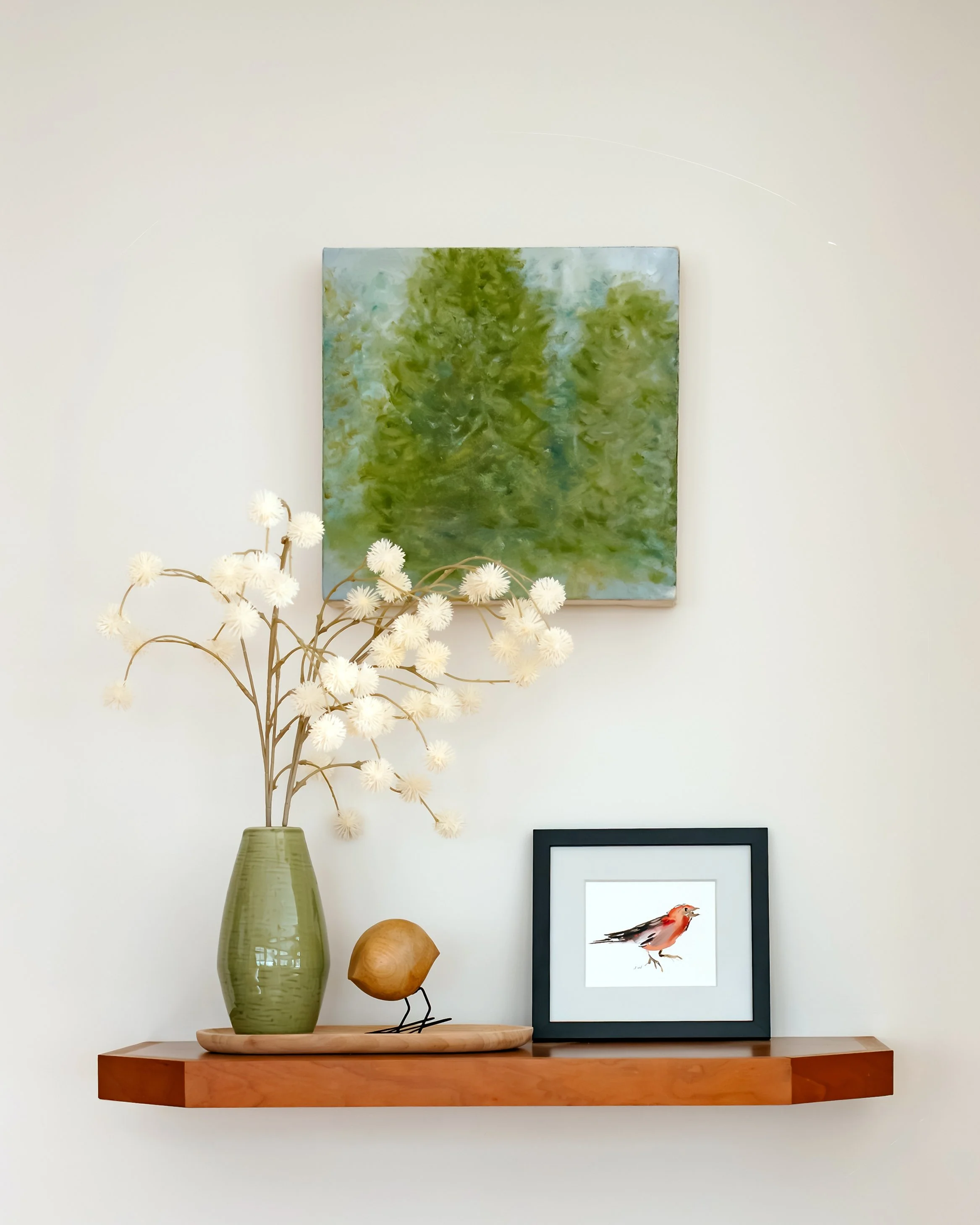 Minimal shelf styling with ceramic vase, framed bird artwork, and abstract painting.