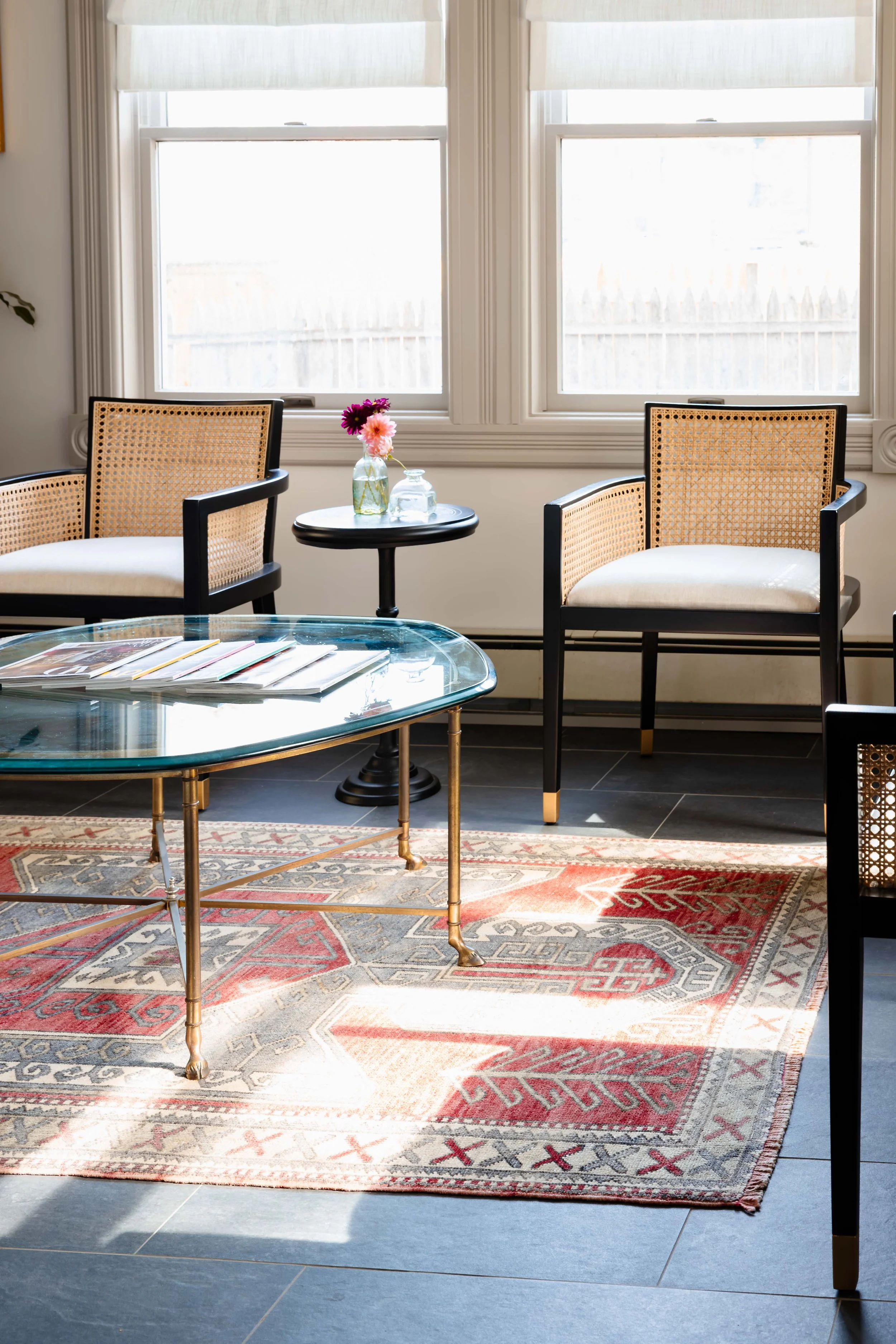 Client waiting area with cane chairs, glass coffee table, and vintage rug in New Paltz NY
