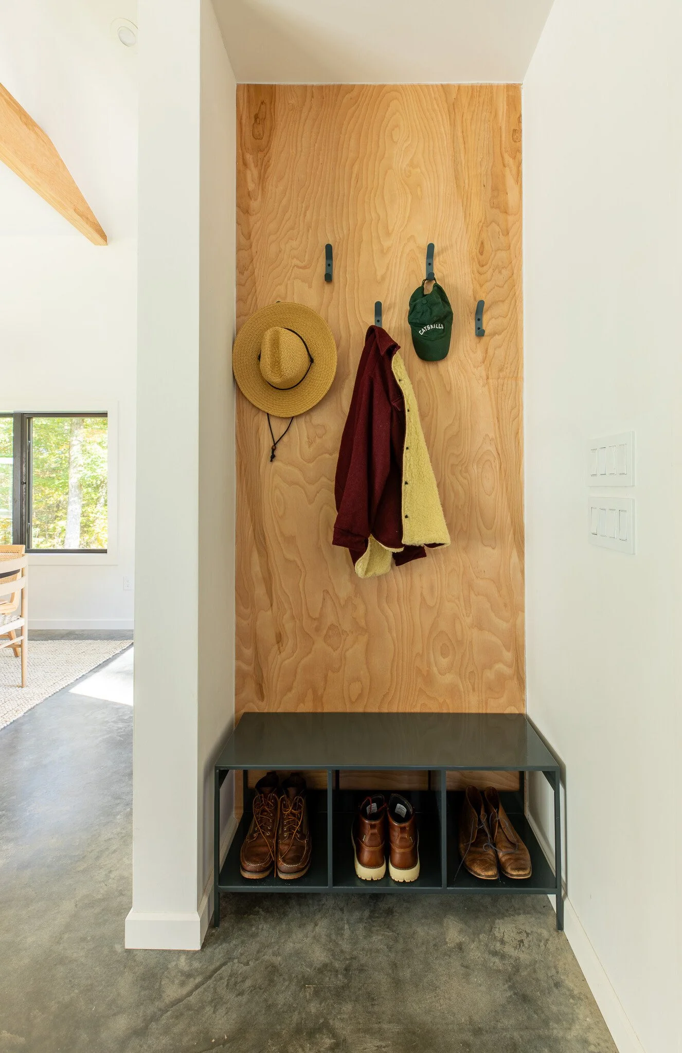 Entry room with wall hooks, wood panel accent, and bench with shoe storage below.