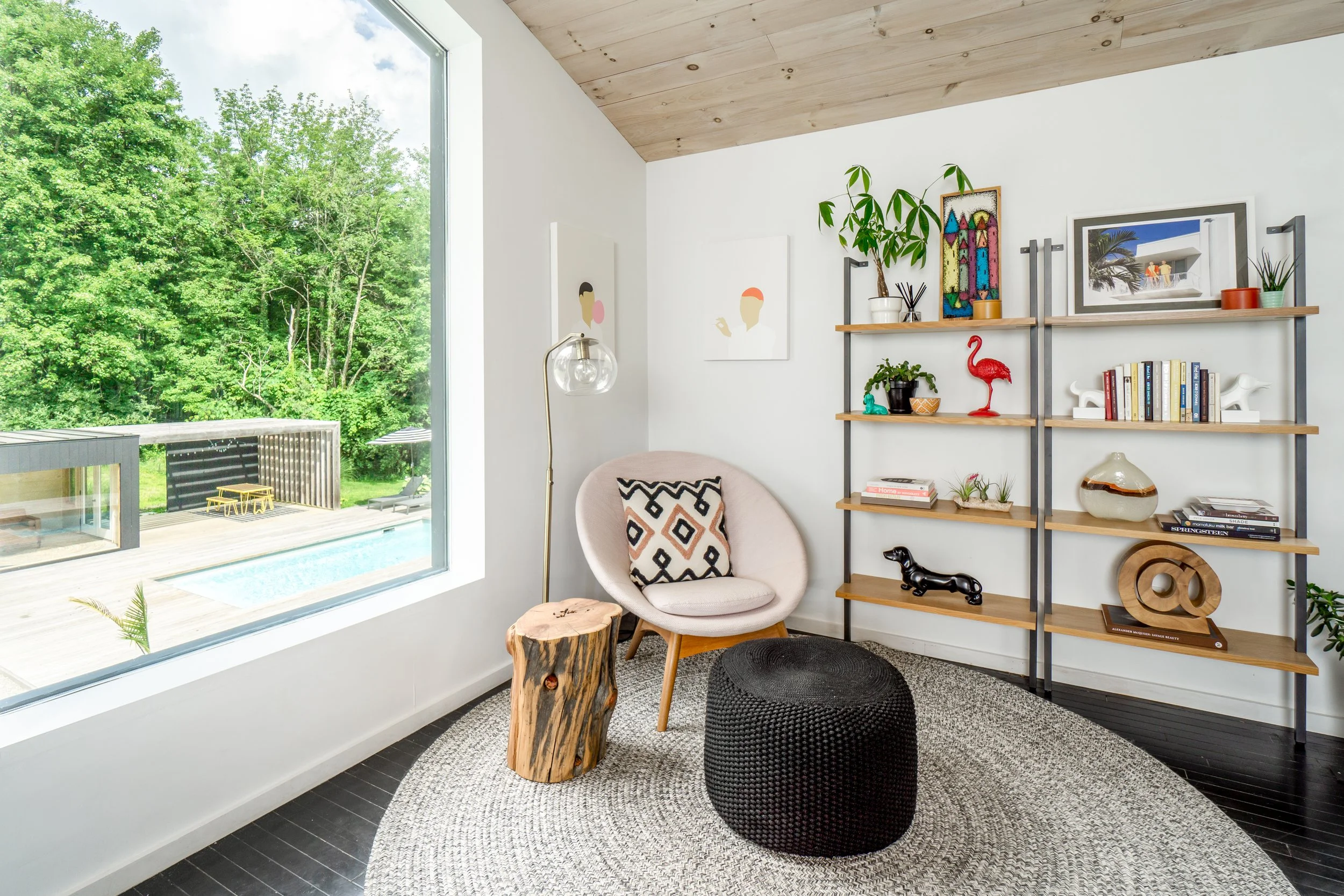 Cozy reading nook with round chair, wood stump side table, and styled open shelving.