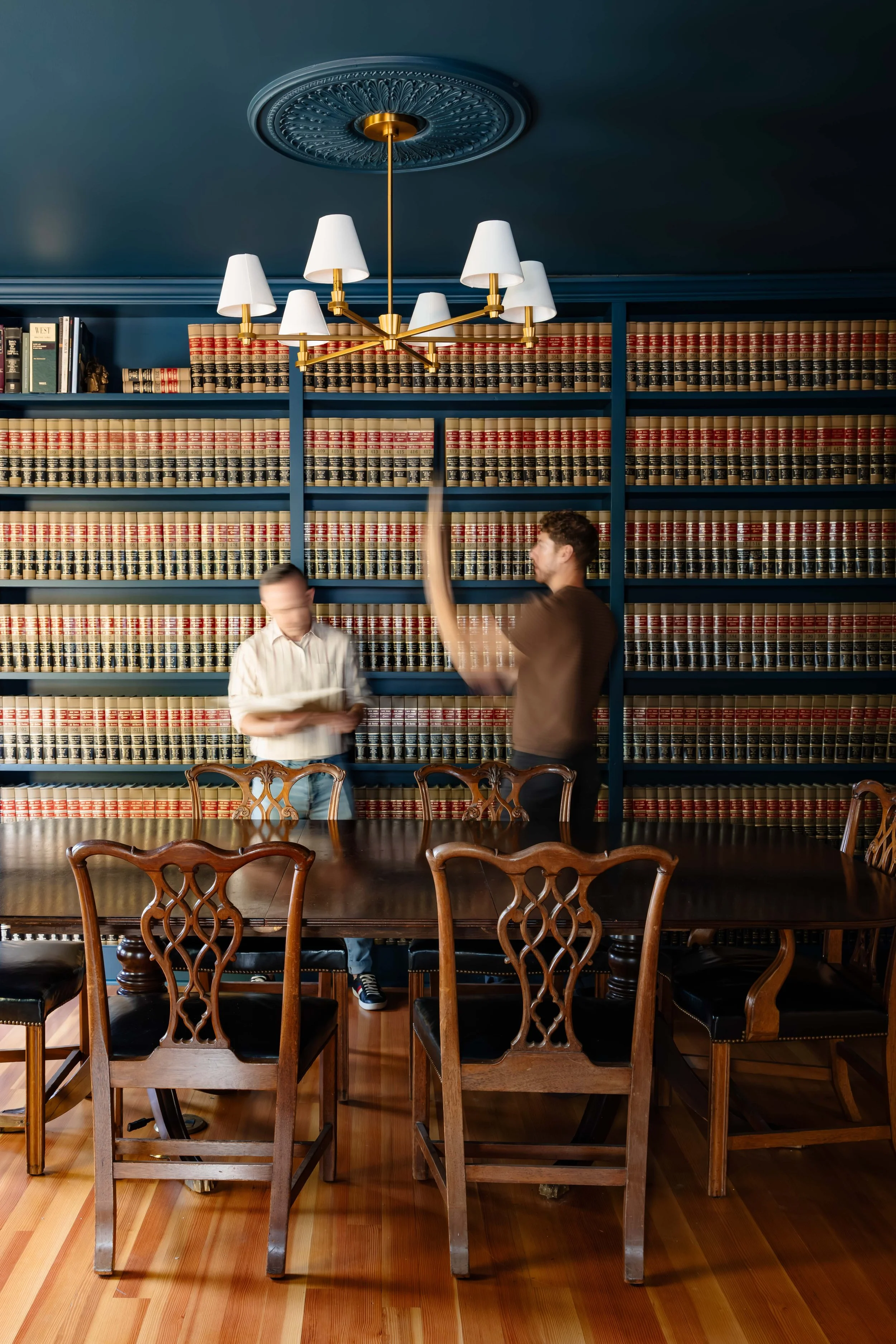 Conference room with floor-to-ceiling law bookcases, antique wood table, and brass chandelier in historic New Paltz office