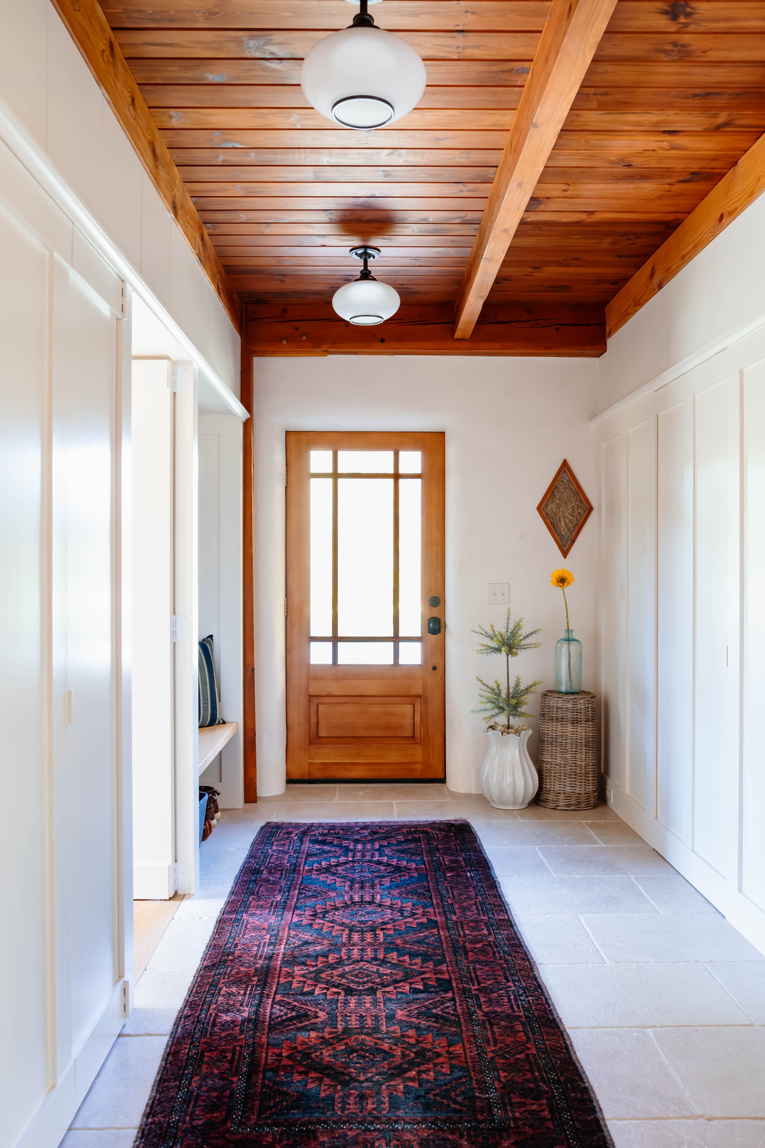 Entry hallway renovation in a straw bale home featuring limestone flooring, custom wall paneling, and exposed wood ceiling beams in New Paltz, NY.